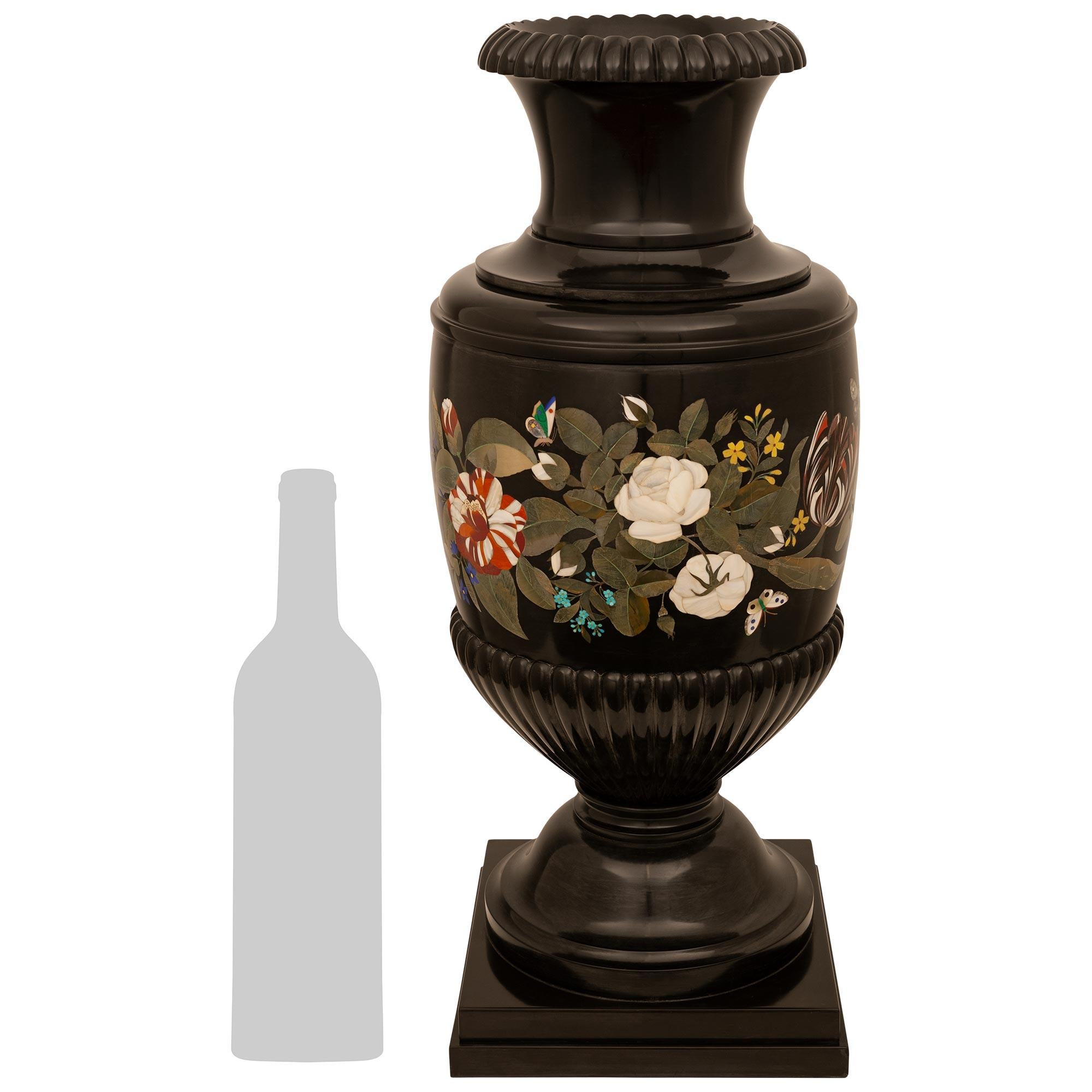 Un sensazionale vaso di grandi dimensioni in marmo belga nero e PIETRA DURA del XIX secolo. Questo meraviglioso vaso è sollevato su una base quadrata in marmo belga sotto un piedistallo circolare a socle. La base dell'urna, con i suoi bordi a