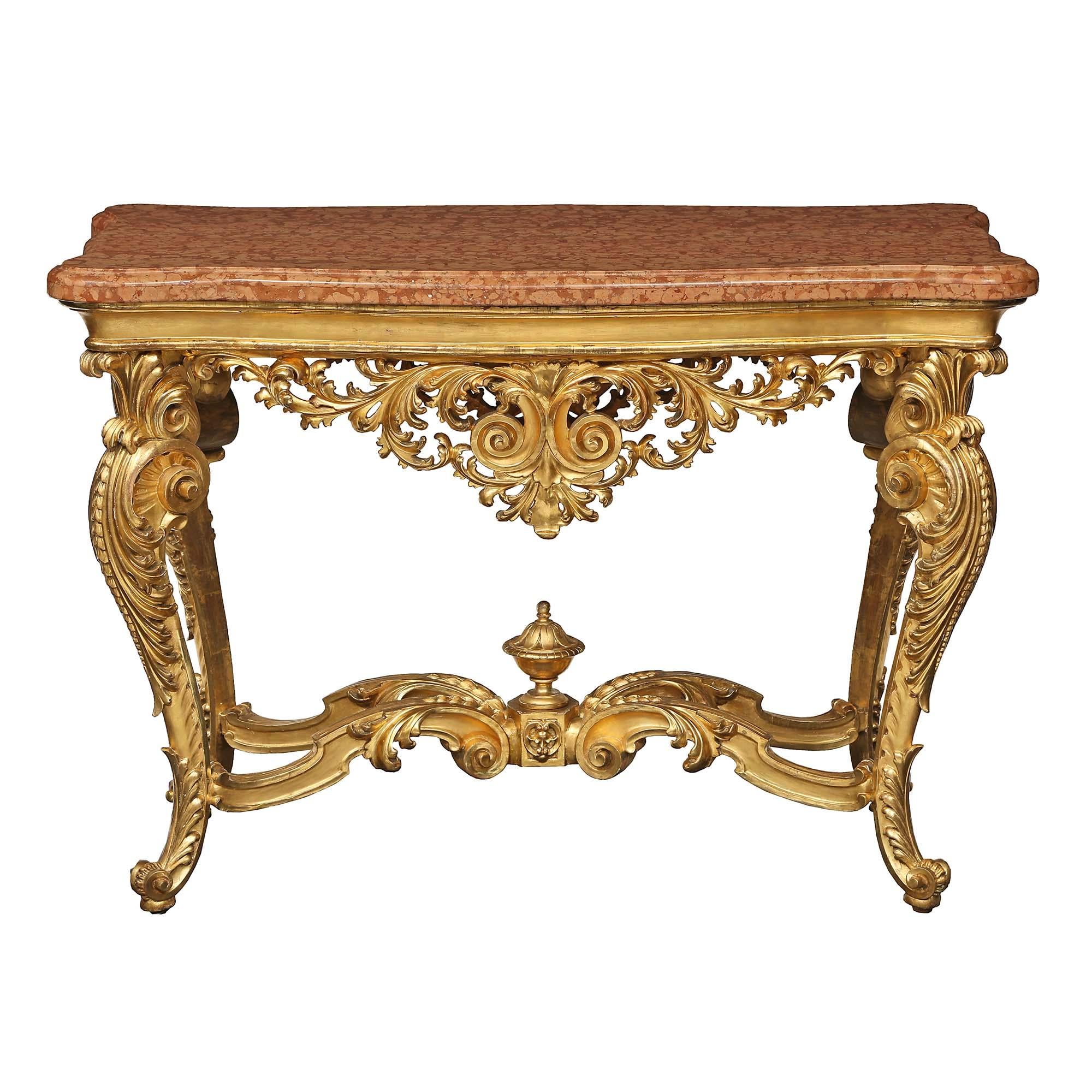 An exceptional Italian 19th century Louis XV st. giltwood center table. The table is raised on elaborately scrolled cabriole legs accented with large scrolls and acanthus leaves. The legs are joined by a scrolled X stretcher centered by hexagon