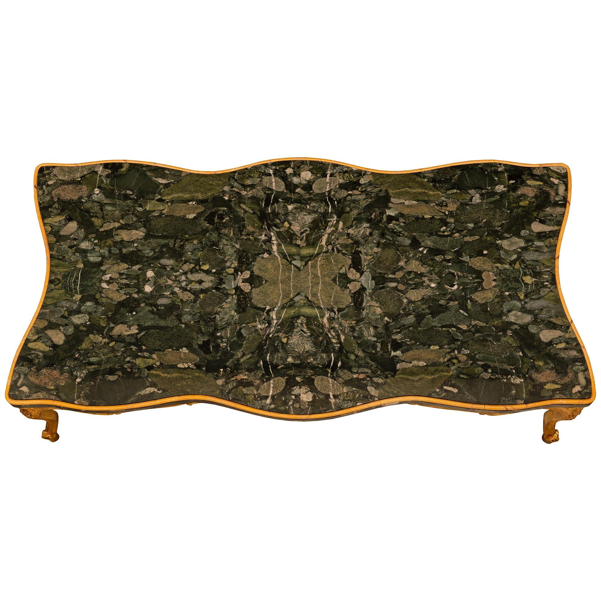 Charmante table basse en bois doré, marbre de Sienne et marbre Breccia Pavonazza de style Louis XV italien du 19e siècle, finement détaillée. Cette magnifique table repose sur quatre pieds cabriole en bois doré à volutes, chaque pied étant surmonté