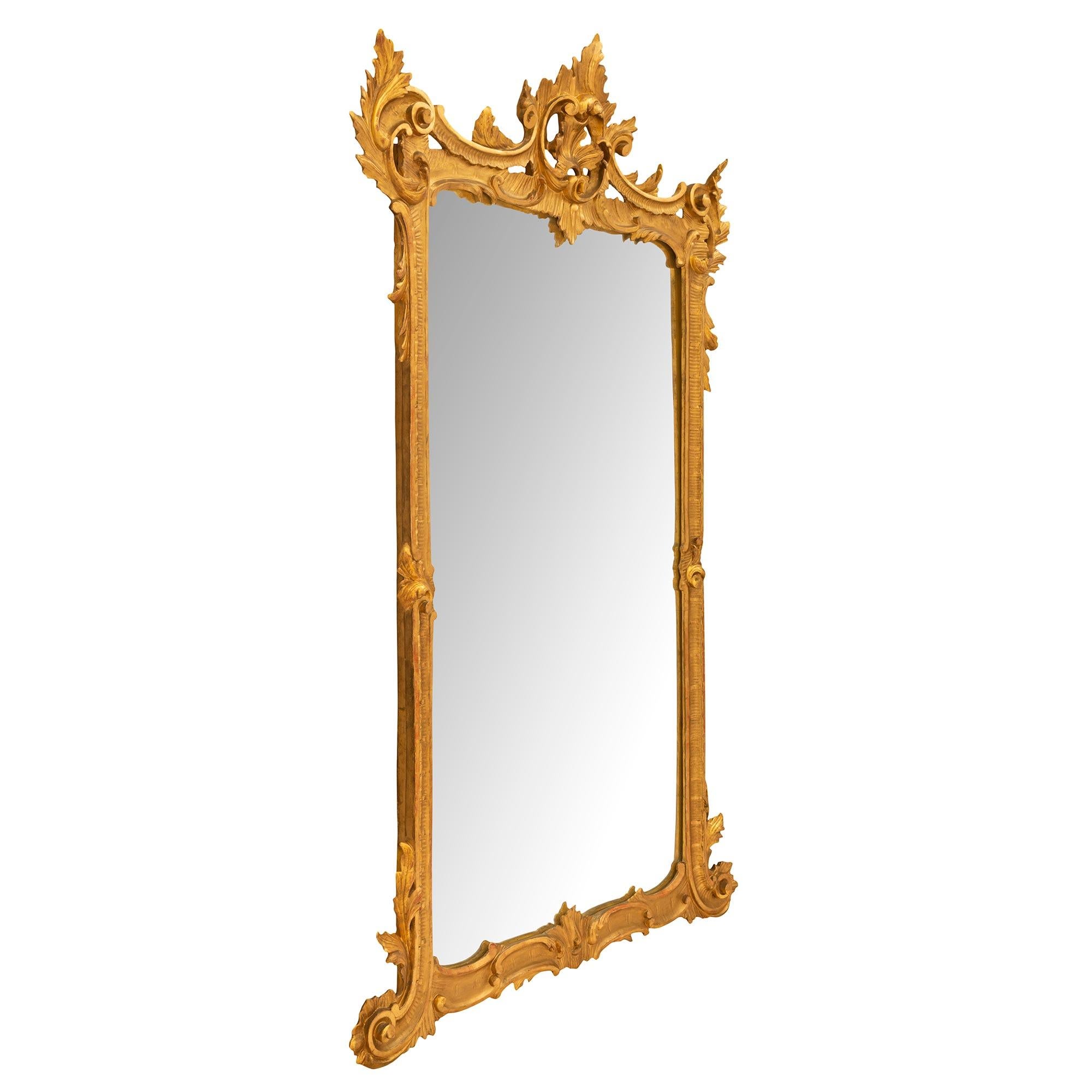 Merveilleux miroir italien du 19ème siècle en bois doré de style Louis XV. La plaque de miroir d'origine est encadrée dans une saisissante et unique bordure en bois doré mouluré avec d'élégants mouvements en forme de C. Le fond est orné de riches