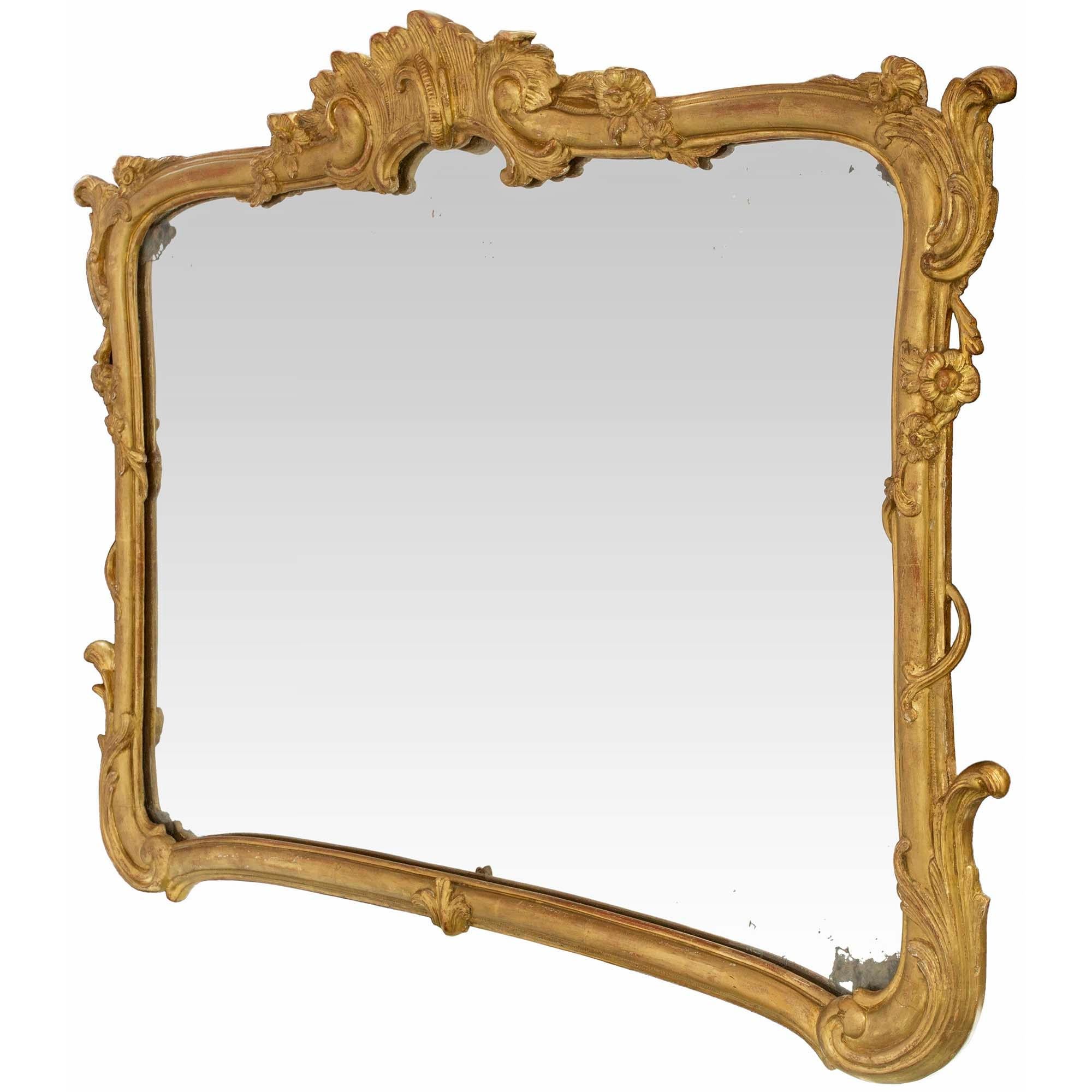 Merveilleux miroir italien du 19ème siècle en bois doré de style Louis XV. La plaque de miroir d'origine est encadrée d'une fine bordure mouchetée avec des feuilles d'acanthe sculptées et des réserves florales. Ci-dessus, la couronne supérieure la