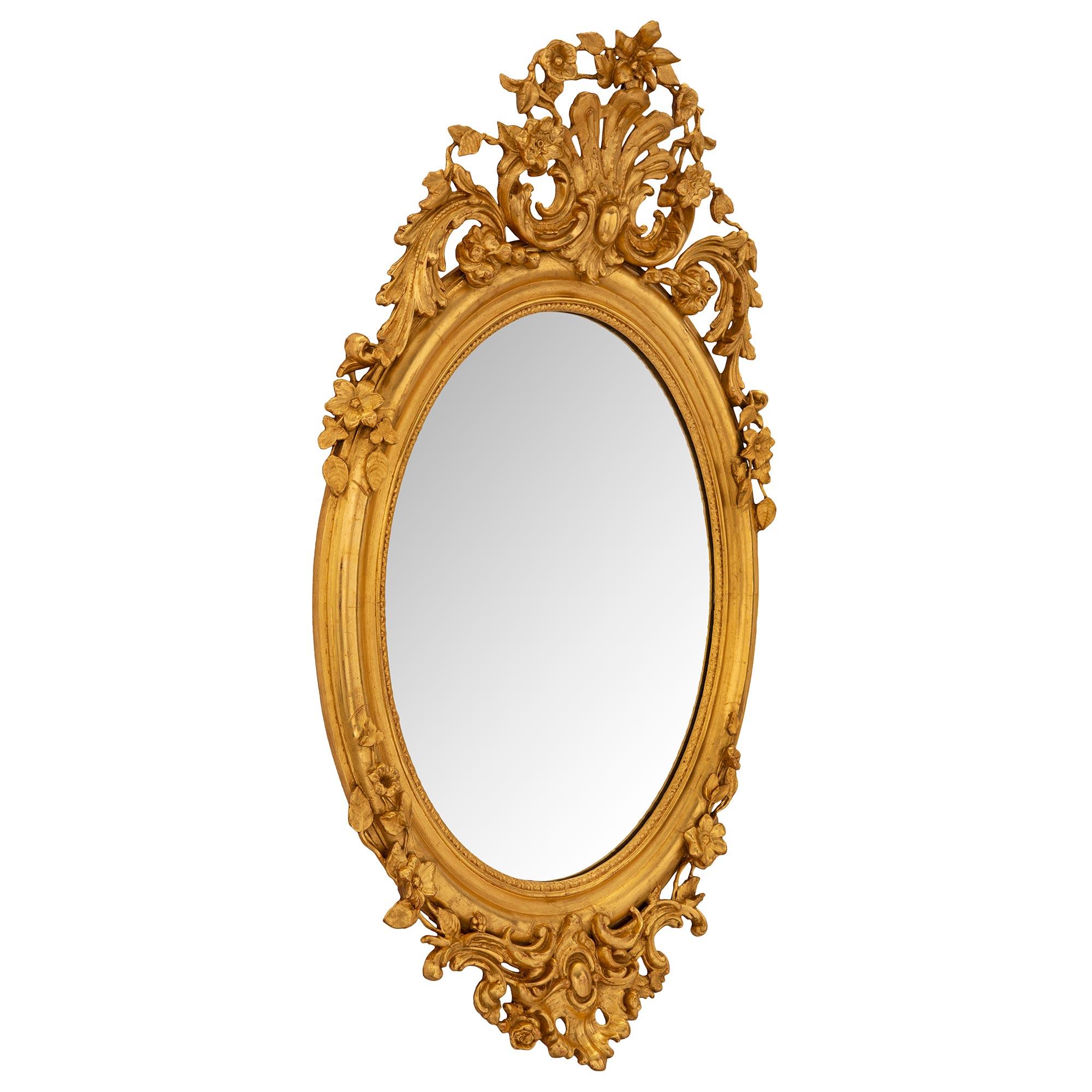 A striking and most elegant Italian 19th century Louis XV st. giltwood mirror. The oval mirror retains its original mirror plate set within a fine mottled framed with a lovely wrap around foliate band. At the base is a superb foliate reserve with a