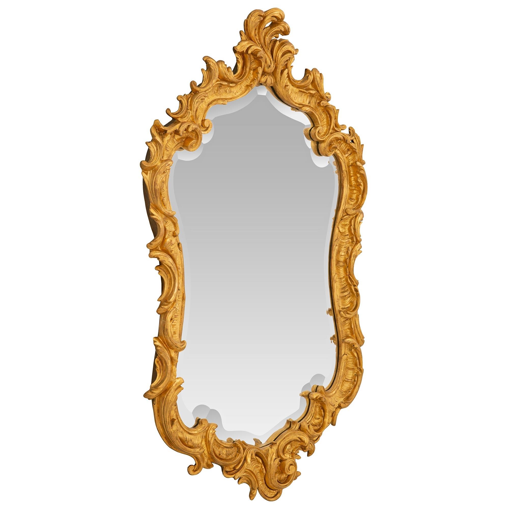An outstanding Italian 19th century Louis XV st. giltwood mirror. The mirror retains its original beveled mirror plate set within the wonderful and most decorative giltwood frame. The frame displays stunning richly carved scrolled foliate designs