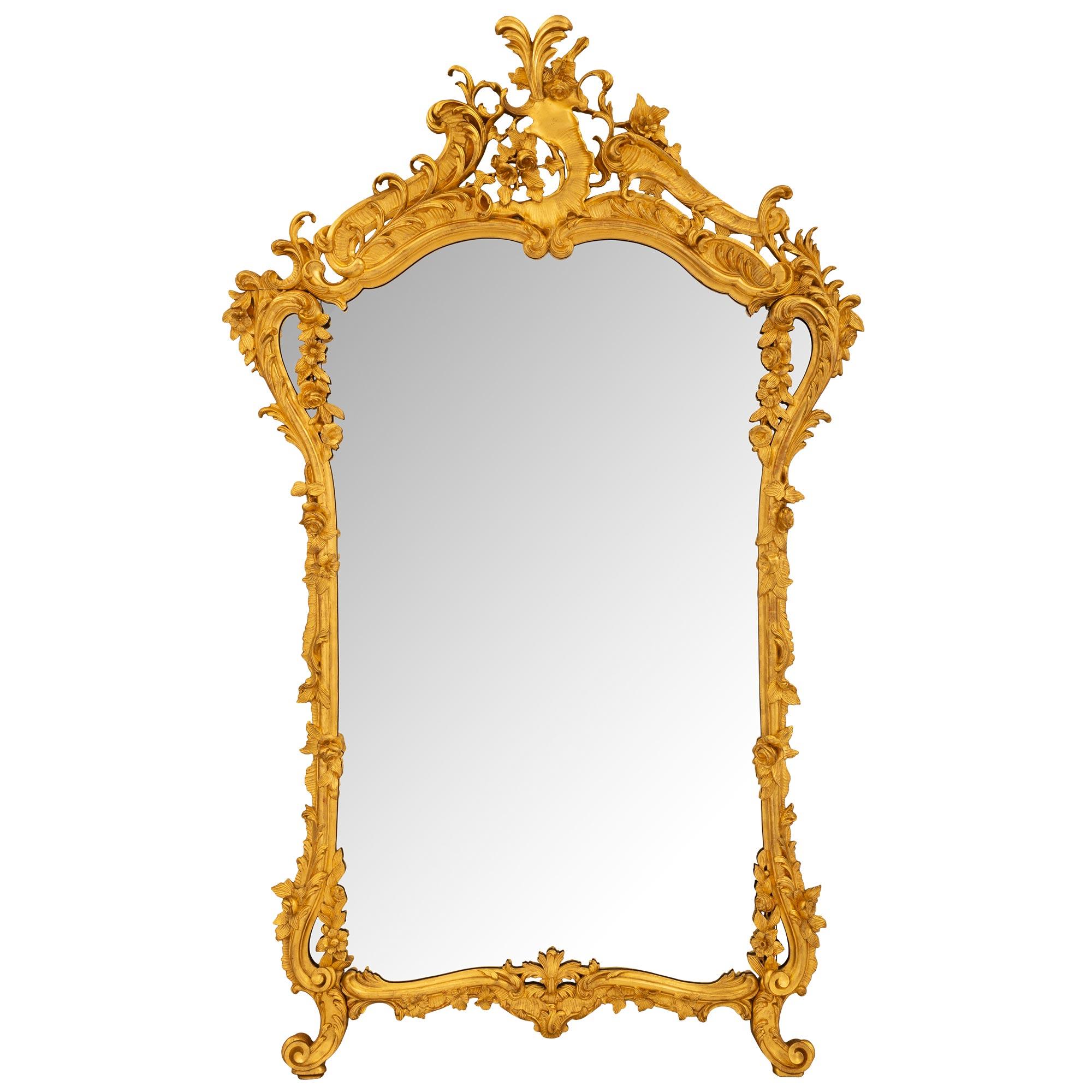 A beautiful and impressive Italian 19th century Louis XV st. giltwood mirror. The mirror retains its original mirror plate set within a lovely scalloped shaped mottled band. At the base are lovely elegantly scrolled feet flanking a beautiful foliate