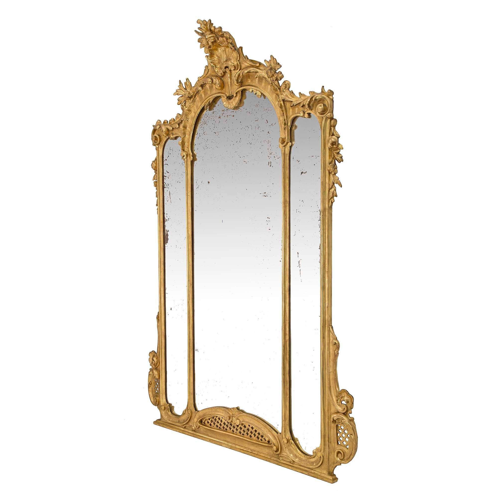 A handsome and large scale Italian 19th century Louis XV st. giltwood mirror. The mirror has three mirror plates within the double frame. At the straight base are lovely foliate scrolls and a pierced rosette design repeated at each side. At the top