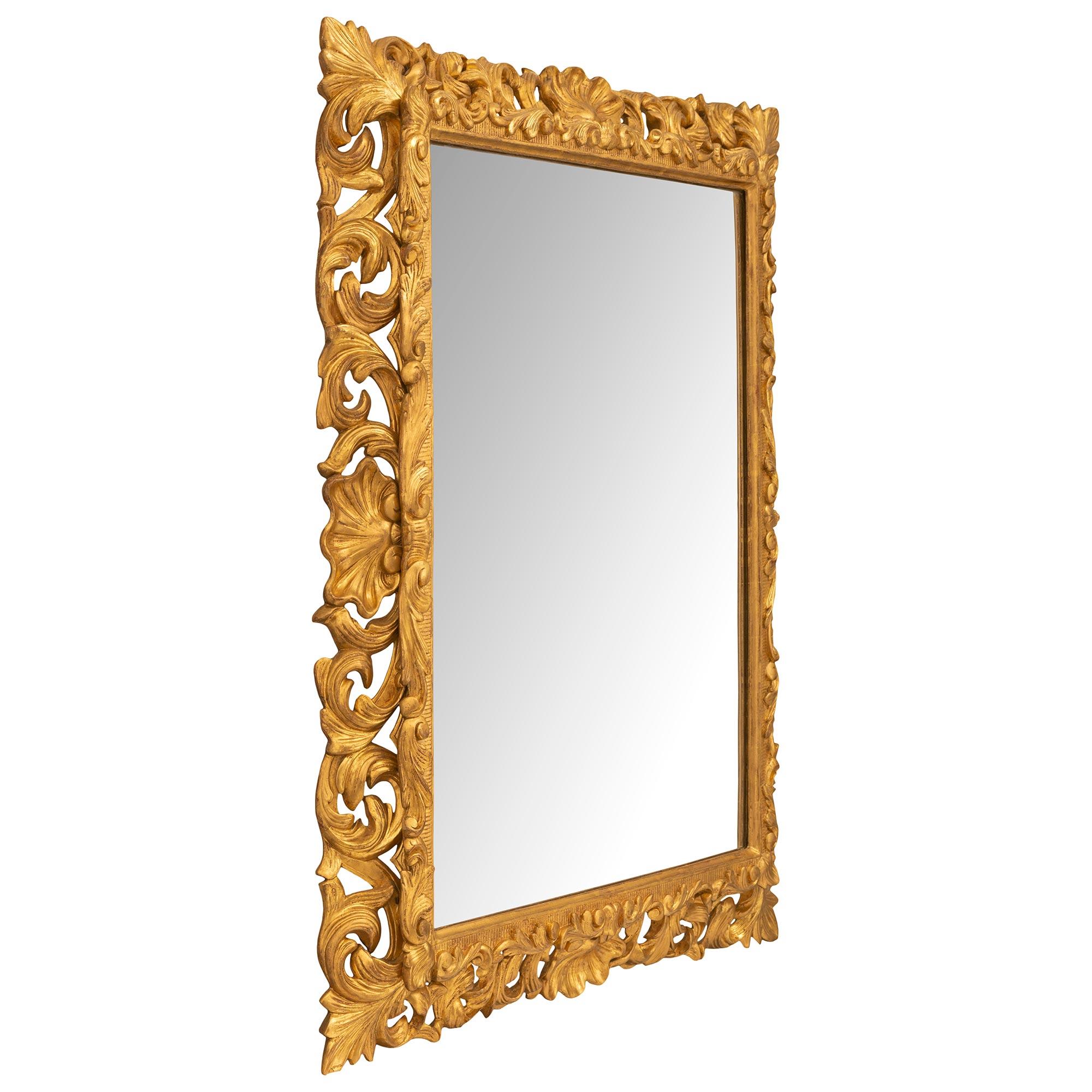 Magnifique miroir italien en bois doré de style Louis XV, datant du 19ème siècle et provenant de Florence. Le miroir conserve sa plaque d'origine encadrée d'une fine bordure droite tachetée avec de jolis motifs cannelés. Tout au long du cadre se