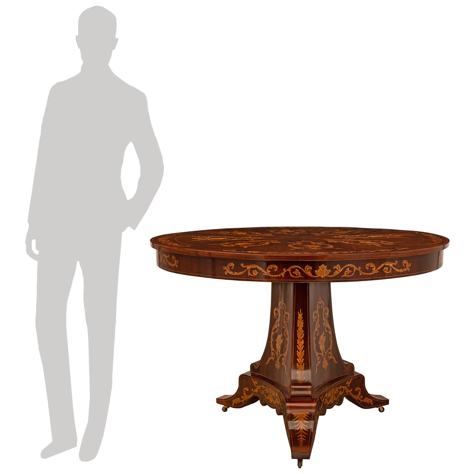 Un eccezionale e decoratissimo tavolo da centro in noce e legno di frutto del XIX secolo Luigi XV. Questo tavolo circolare di alta qualità è sollevato da rotelle che conducono a tre sostegni fino alla colonna centrale triangolare affusolata con i
