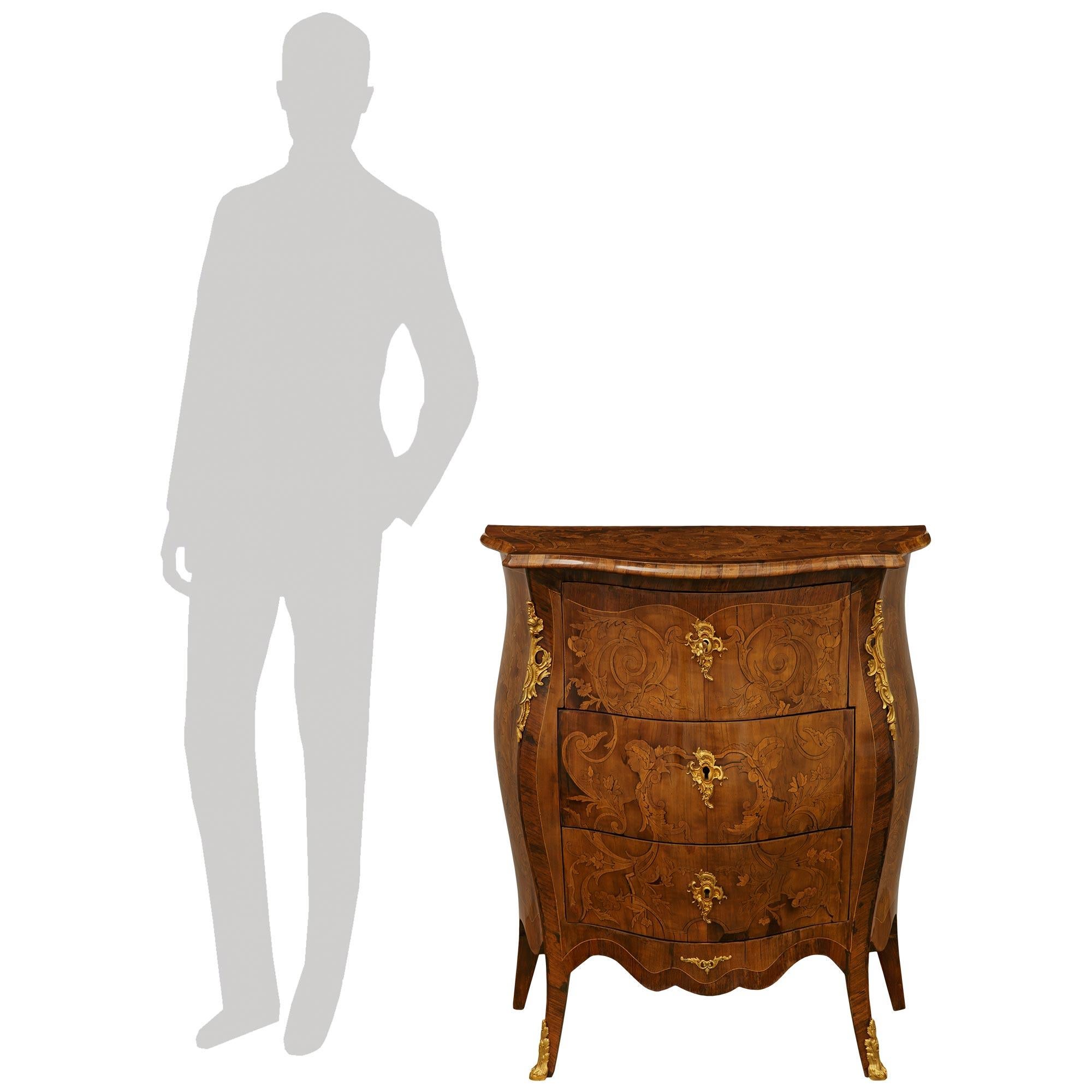 A stunning and most decorative Italian 19th century Louis XV st. Walnut and Ormolu commode. This exquisite bombee shaped three drawer commode is raised on stout cabriole legs fitted with foliate Ormolu sabots below the arbalest shaped apron accented