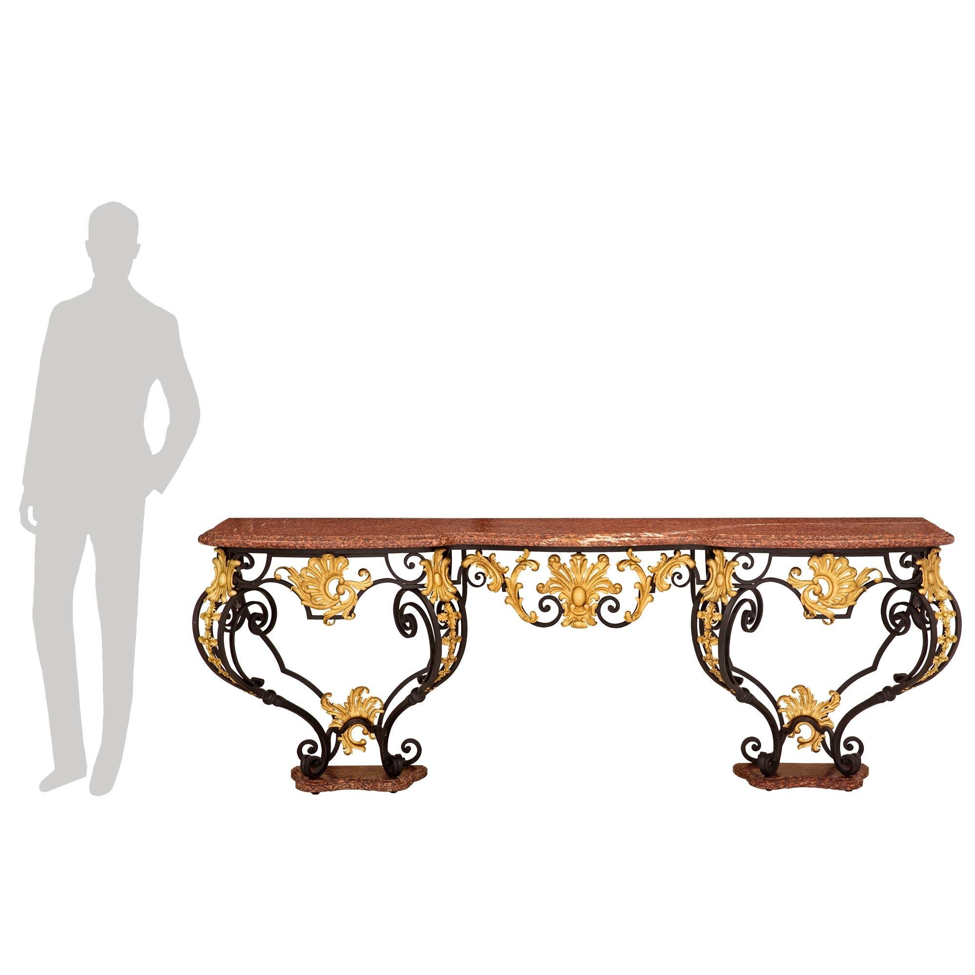 A stunning Italian 19th century Louis XV st. wrought iron, gilt metal, and Rouge Campan marble console. The most impressive wall mounted console is raised by unique marble feet with a most decorative scalloped shape, a mottled border, and fine iron