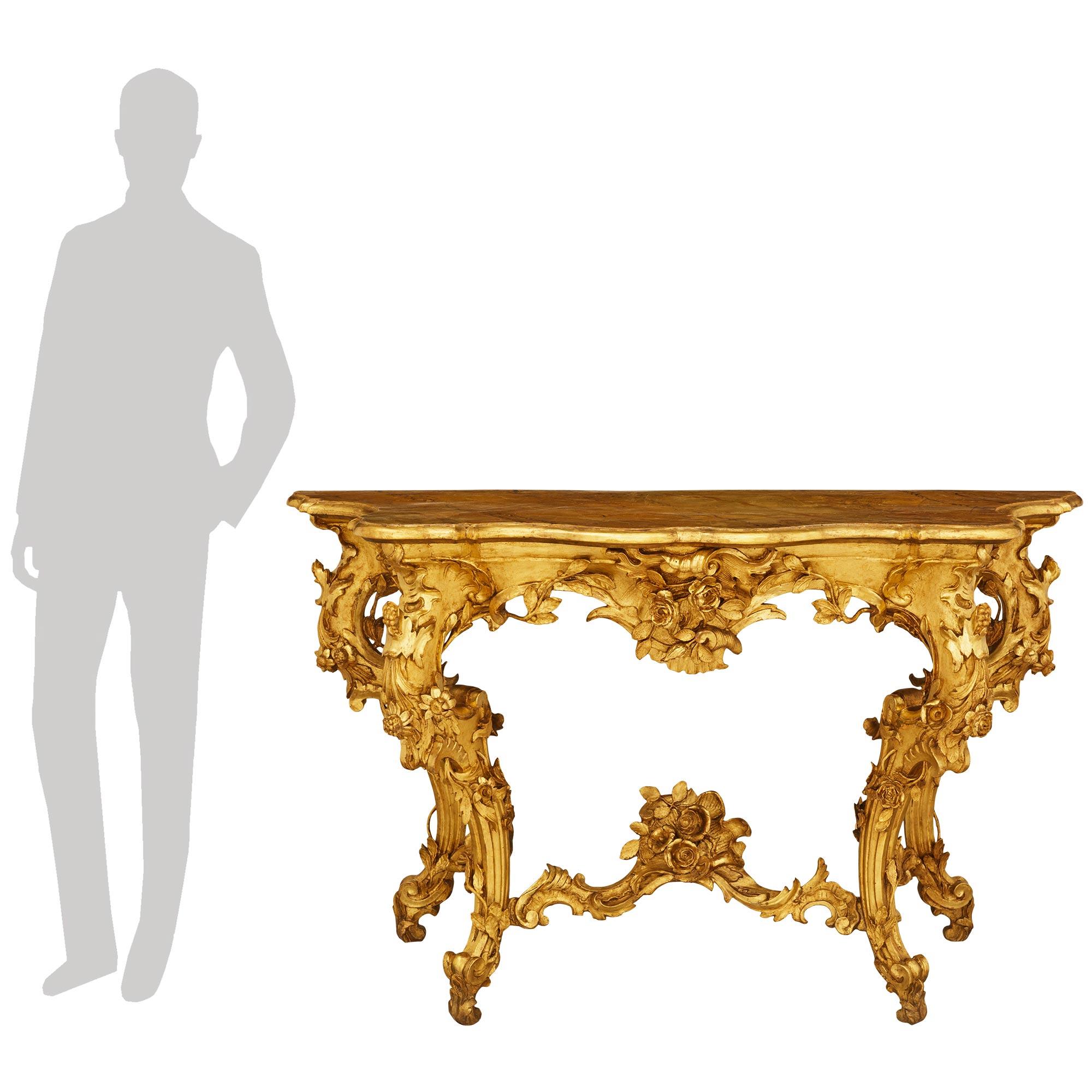 Impresionante consola independiente italiana del siglo XIX, de estilo Luis XV, finamente tallada en madera dorada. La impresionante consola se eleva sobre patas en forma de S con exquisitas y elaboradas tallas foliadas de flores y ramas envolventes.