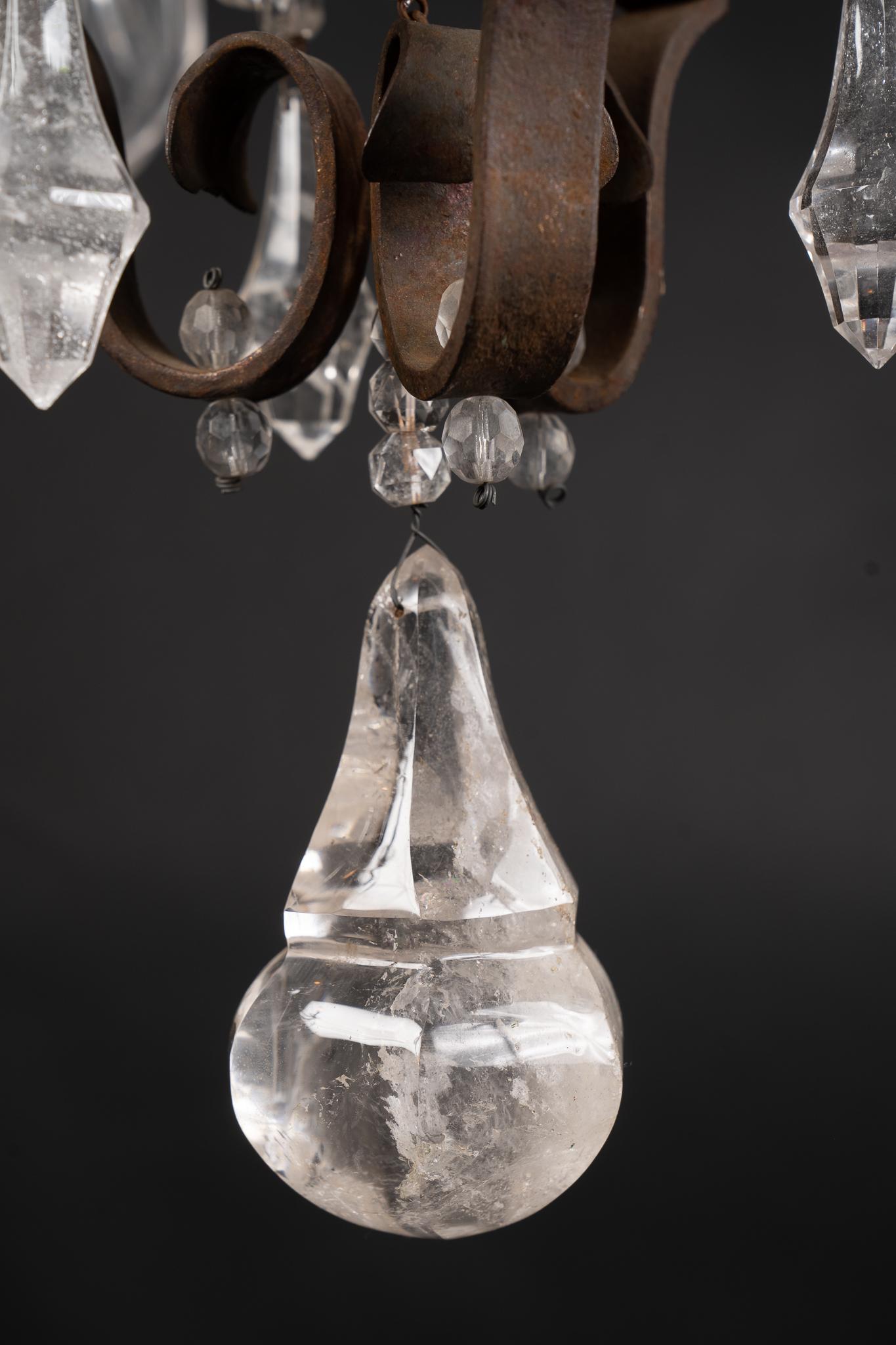 Questo maestoso lampadario in ferro battuto è caratterizzato da bobeches in ferro battuto drappeggiate con plaquettes in cristallo di rocca e fleurettes in cristallo di rocca. Il pezzo antico italiano risale al XIX secolo. È rifinito con una