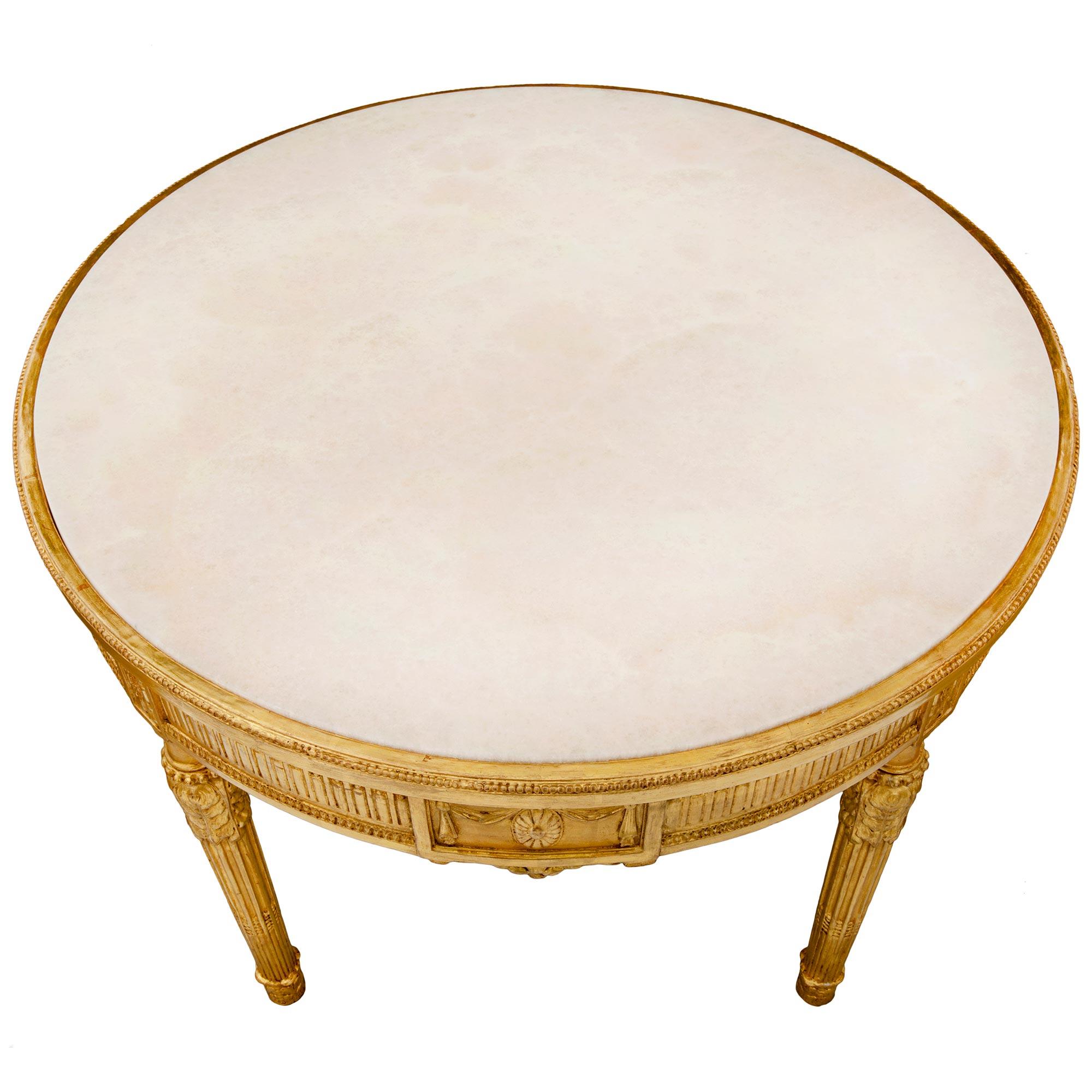 A beautiful Italian 19th century Louis XVI style giltwood and Alabastro Fiorito circular coffee/cocktail table. The table is raised by circular lightly tapered fluted legs with foliate feet and carved acanthus leaves. Above each leg are elegant