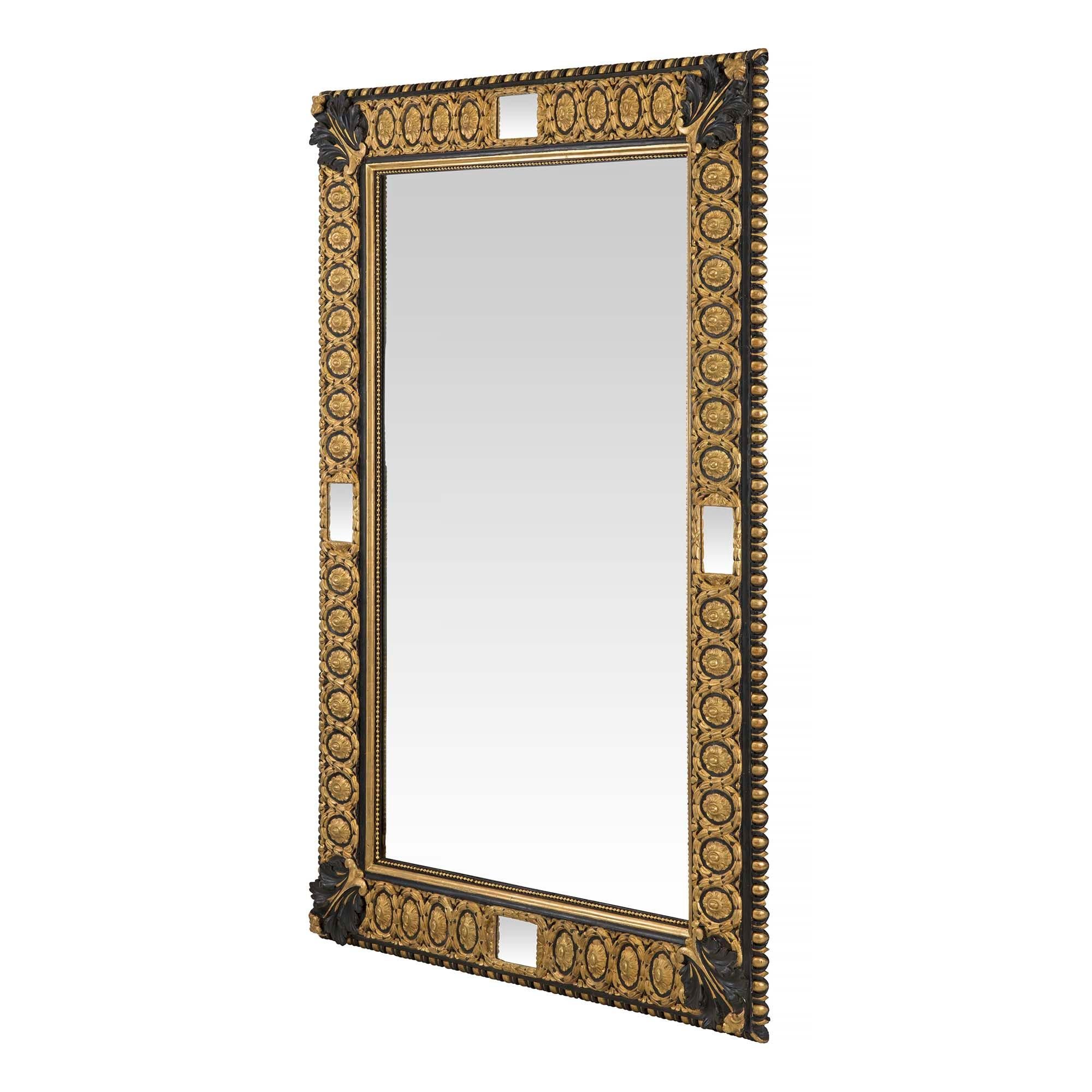 Très beau miroir italien du XIXe siècle, de style Louis XVI, en bois doré et polychrome noir. Le miroir rectangulaire a une garniture intérieure perlée avec une grande vague ovale et un motif de rosette. Au centre de chaque côté se trouve un petit