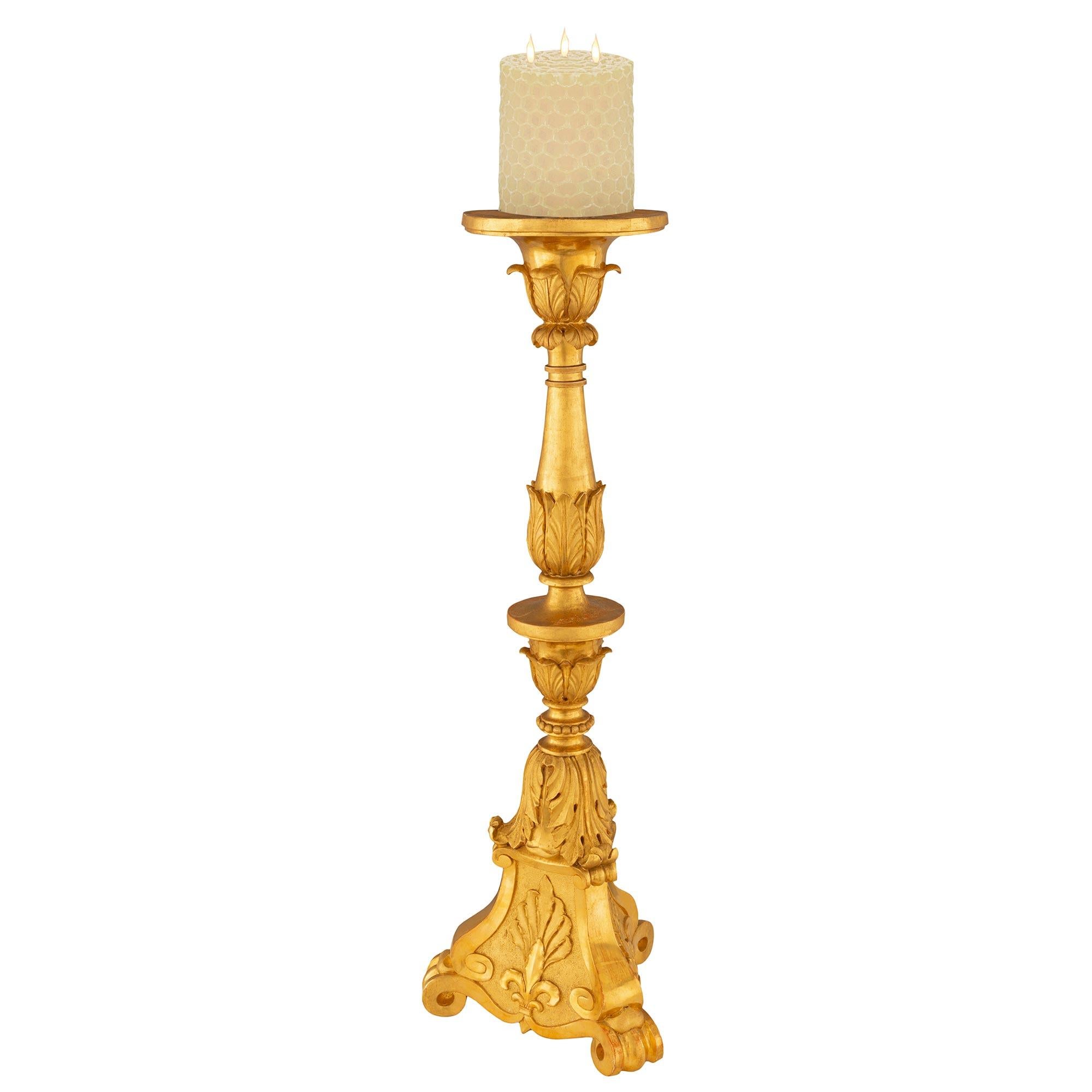 A striking and large scale Italian 19th century Louis XVI st. giltwood candlesticks. Each candlestick is raised by a tapered triangular base with beautiful scrolled feet centering striking palmettes set on a most decorative hammered background. The