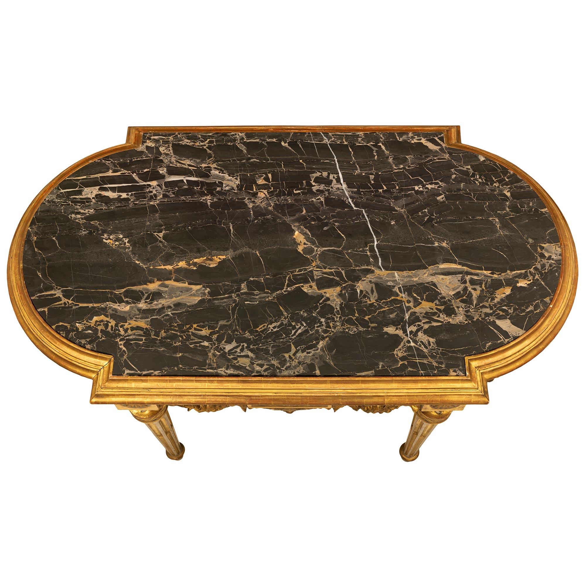 A stunning Italian mid 19th century Louis XVI st. patinated and giltwood center table. The table is raised on tapered reeded legs with a running wave design border below the rosette block top. Centered on each side of the frieze is a rectangular