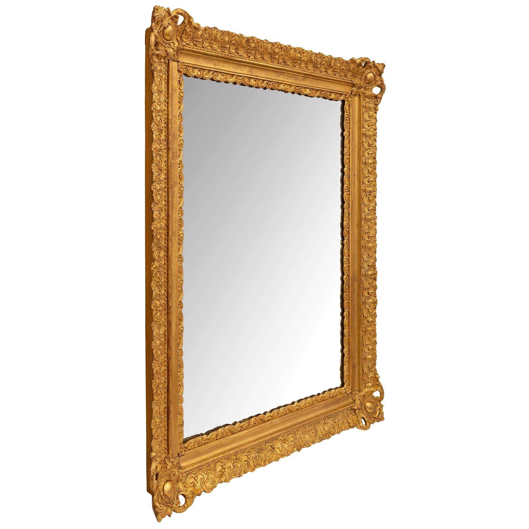 Un'eccezionale e decoratissima specchiera in legno dorato italiano del XIX secolo Luigi XVI. La piastra centrale dello specchio è incorniciata da una fascia foliata smerlata riccamente intagliata con un bel bordo screziato. Il bordo esterno mostra