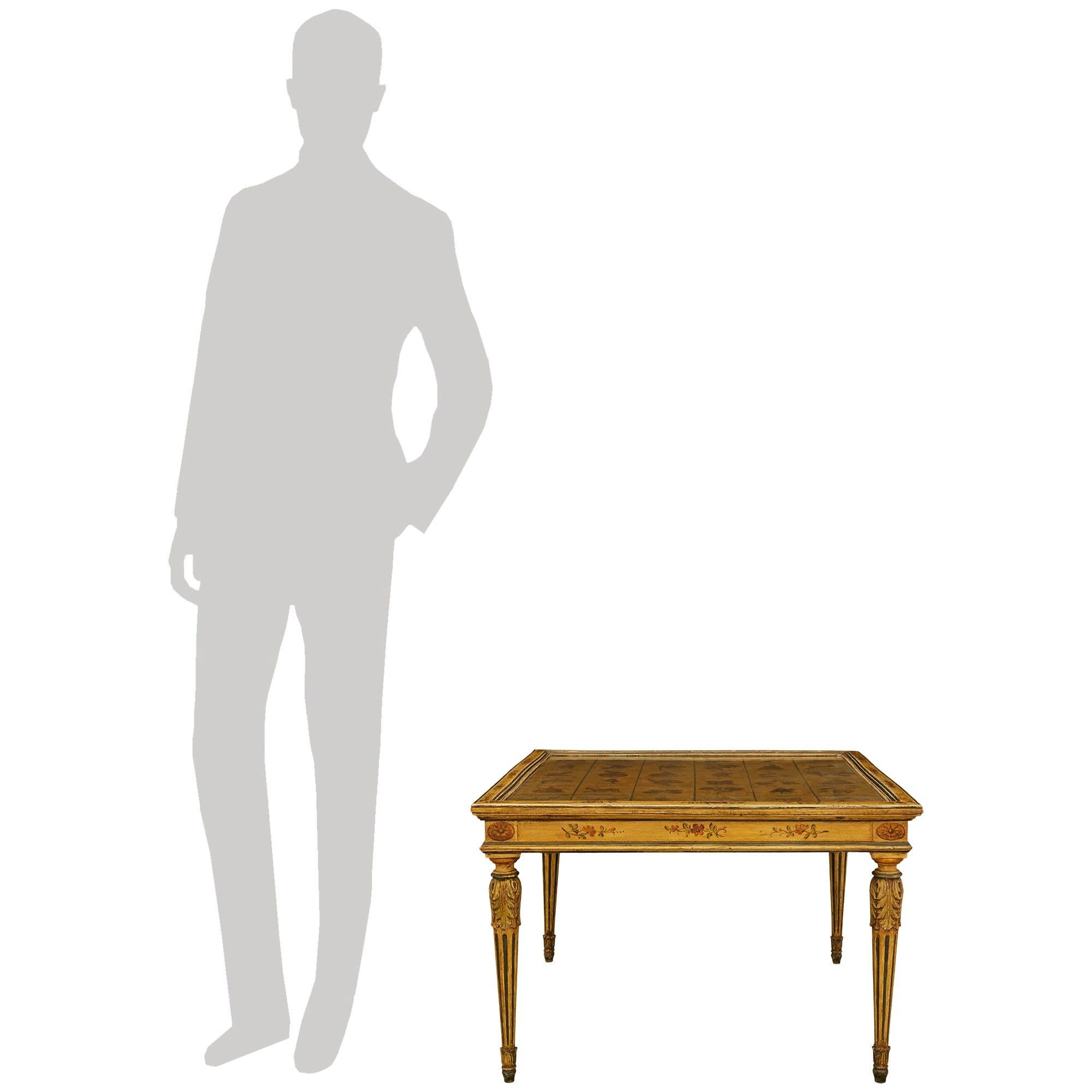 Una mesa de centro de madera patinada y cristal, extremadamente encantadora y única en su género, italiana del siglo XIX, estilo Luis XVI. Esta maravillosa mesa de centro cuadrada patinada en amarillo ilustra un juego de azar italiano, mientras se