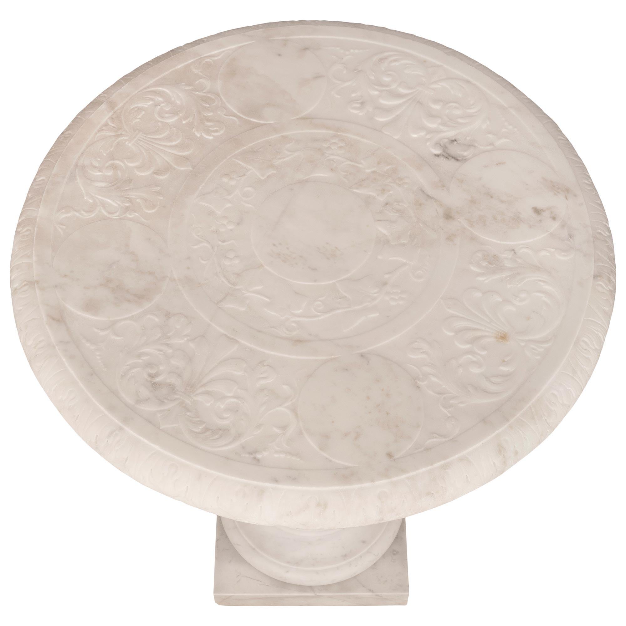 A stunning and most elegant Italian 19th century Louis XVI st. solid white Carrara marble side table. The circular table is raised by a square base with a circular lightly curved mottled support. The baluster shaped column displays exceptional