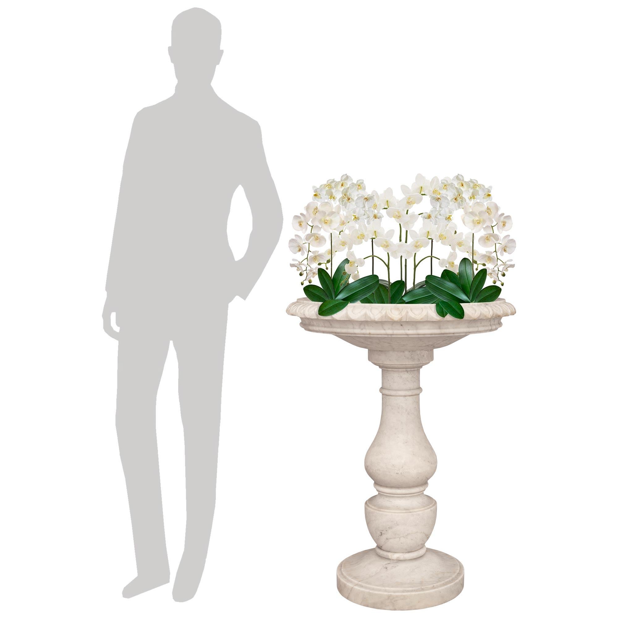 Una splendida ed elegante fioriera in marmo bianco di Carrara del XIX secolo Luigi XVI. Questa imponente vasca per uccelli/pianta è sollevata da una base circolare dal bordo screziato che introduce il fusto screziato finemente decorato che la