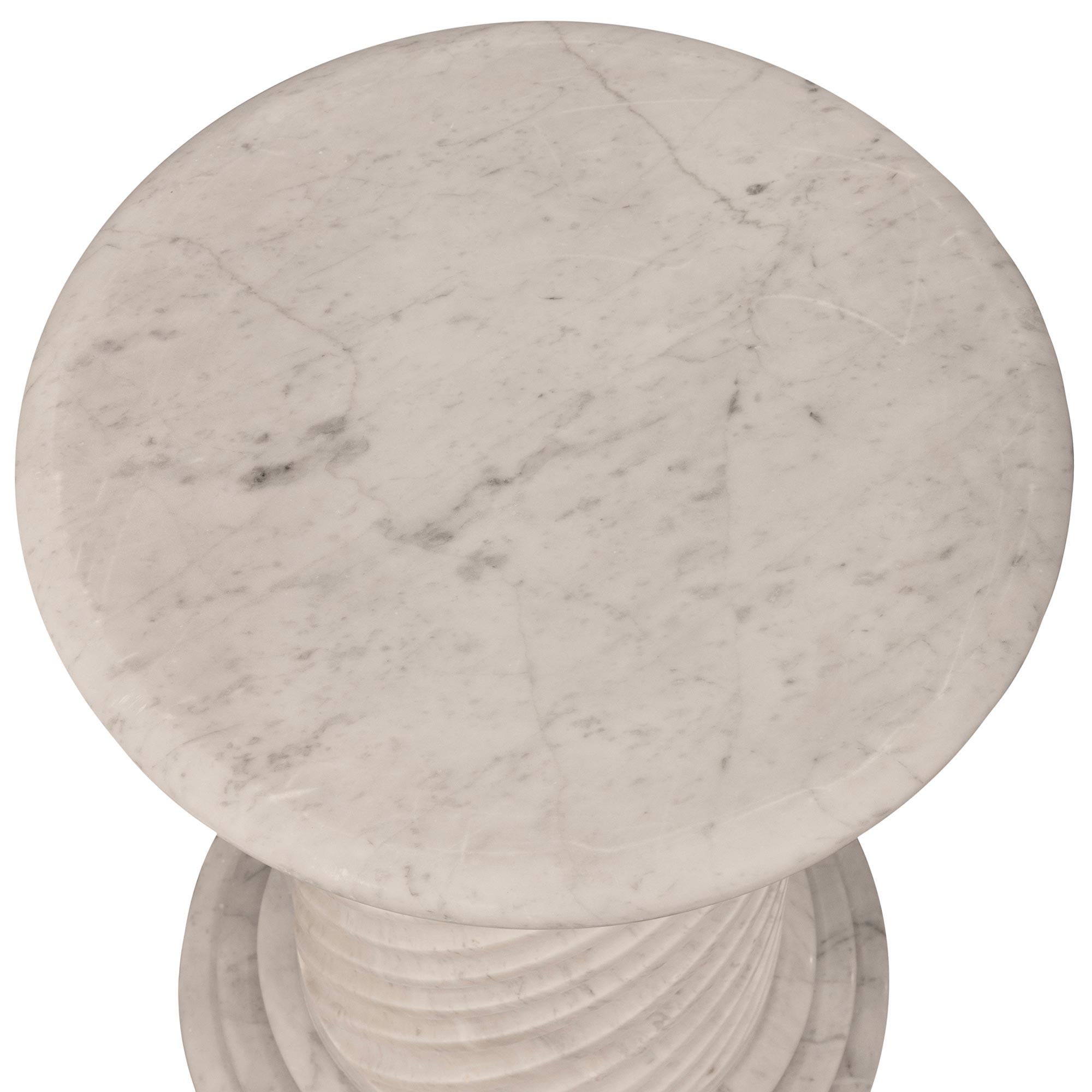 A stunning Italian 19th century Louis XVI st. white Carrara marble pedestal. This exquisite circular pedestal is raised by a three level stepped plinth. The shaft is wonderfully designed with spiral fluted patterns leading up to the capital. The