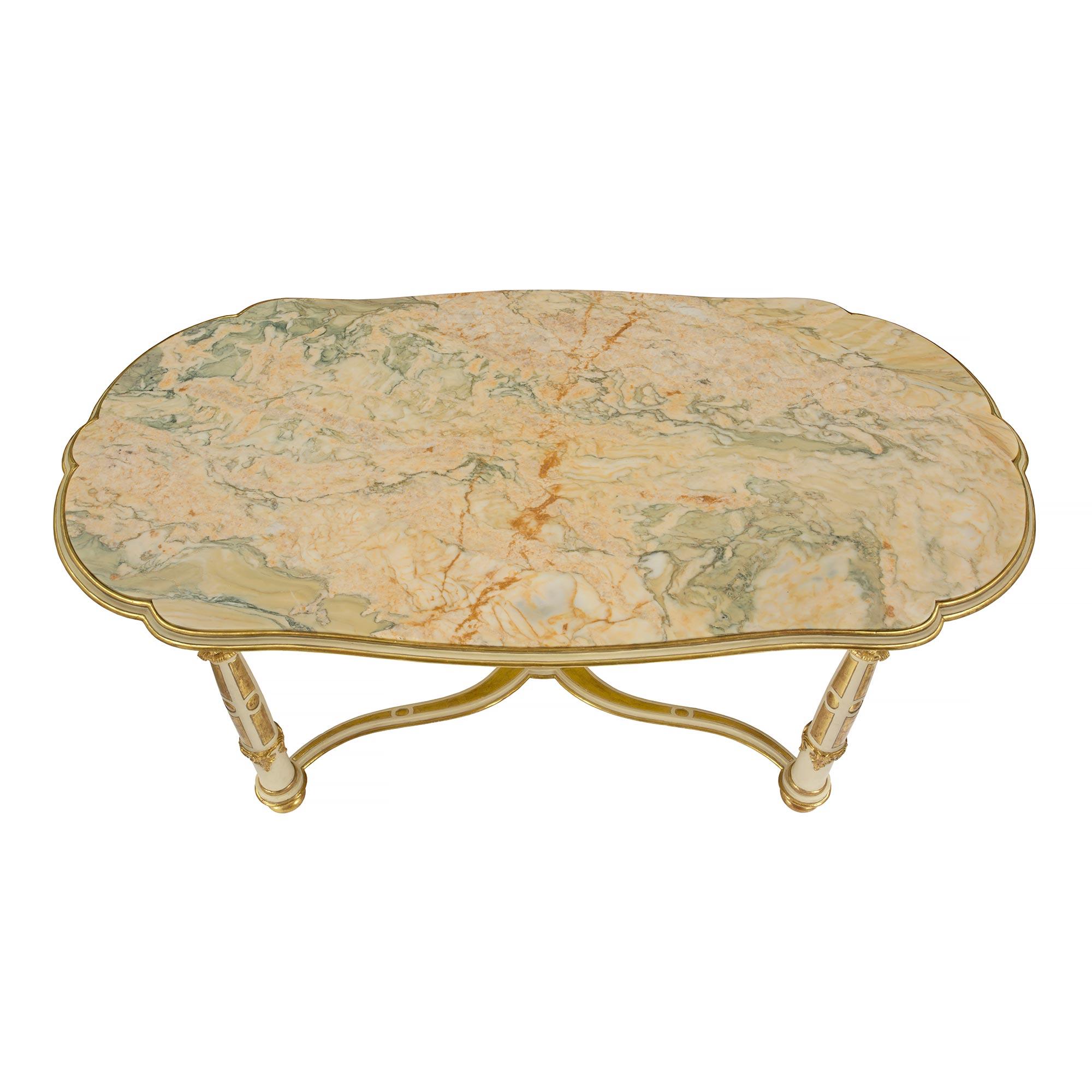 Belle table de centre italienne du 19ème siècle, de style Louis XVI, patinée, en bois doré et marbre. La table est surélevée par de fins pieds en chignon sous d'élégants pieds circulaires. Chaque pied présente de magnifiques motifs feuillus sculptés