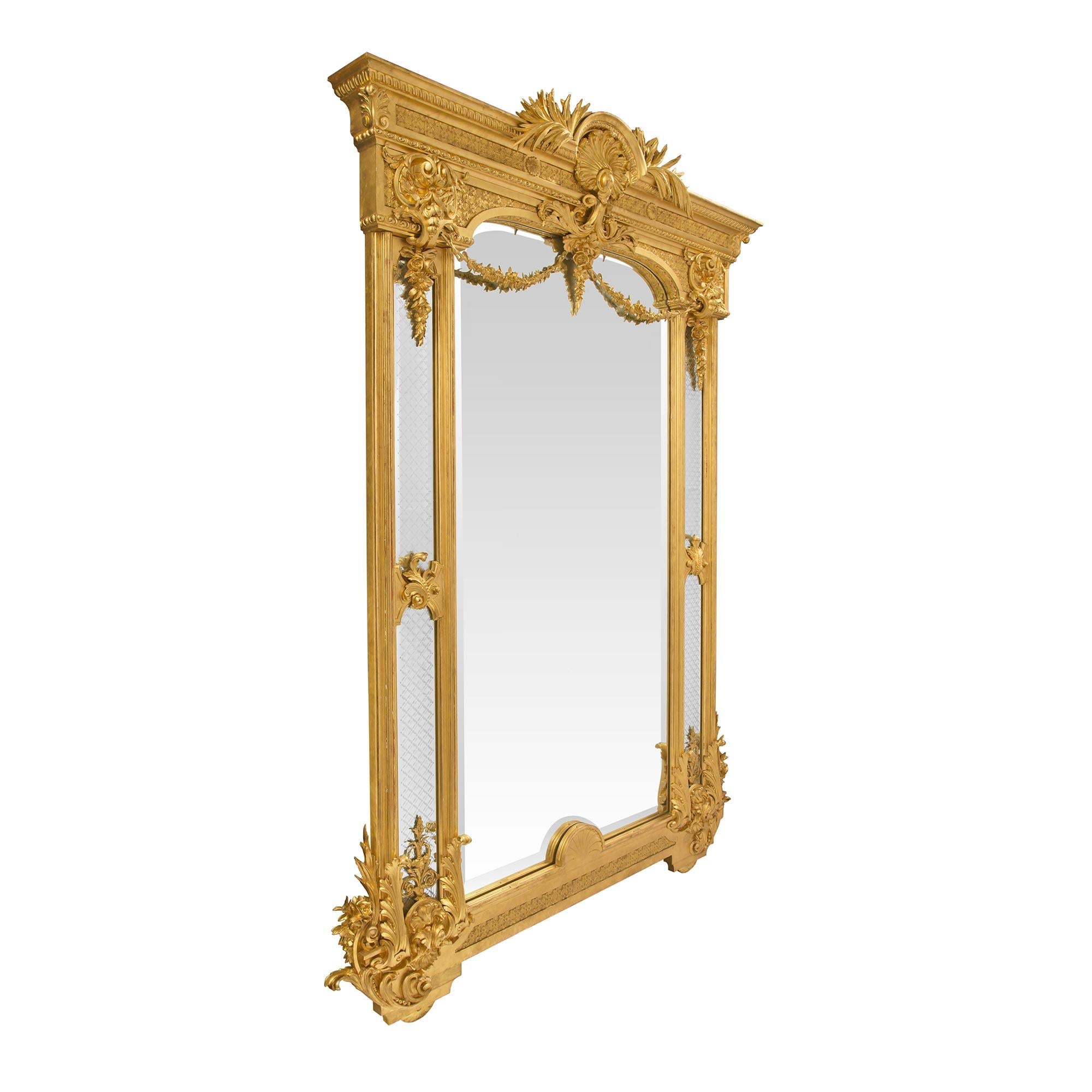 A stunning and monumental Italian 19th century Louis XVI style giltwood double framed mirror. The original central beveled mirror plate is framed within a fine mottled border and displays a beautiful bevel. With a striking recessed bottom carved