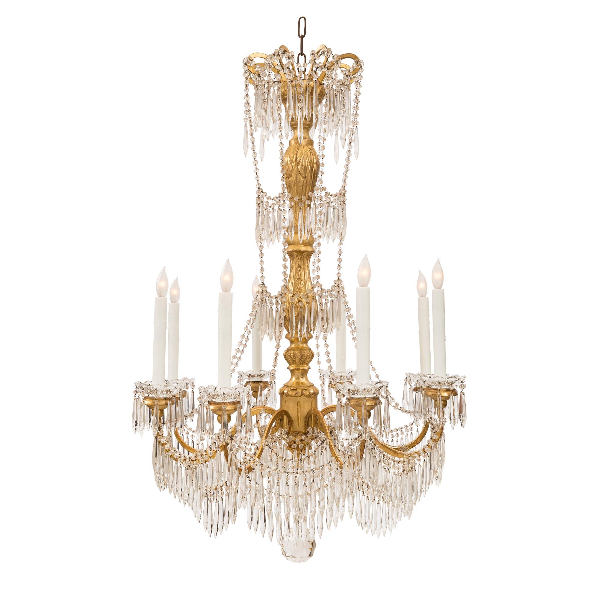 A most elegant Italian early 19th century Louis XVI st. giltwood, gilt metal and crystal eight arm chandelier. The chandelier is centered by a beautiful solid cut crystal ball and a lovely and impressive array of prism shaped cut crystal pendants.