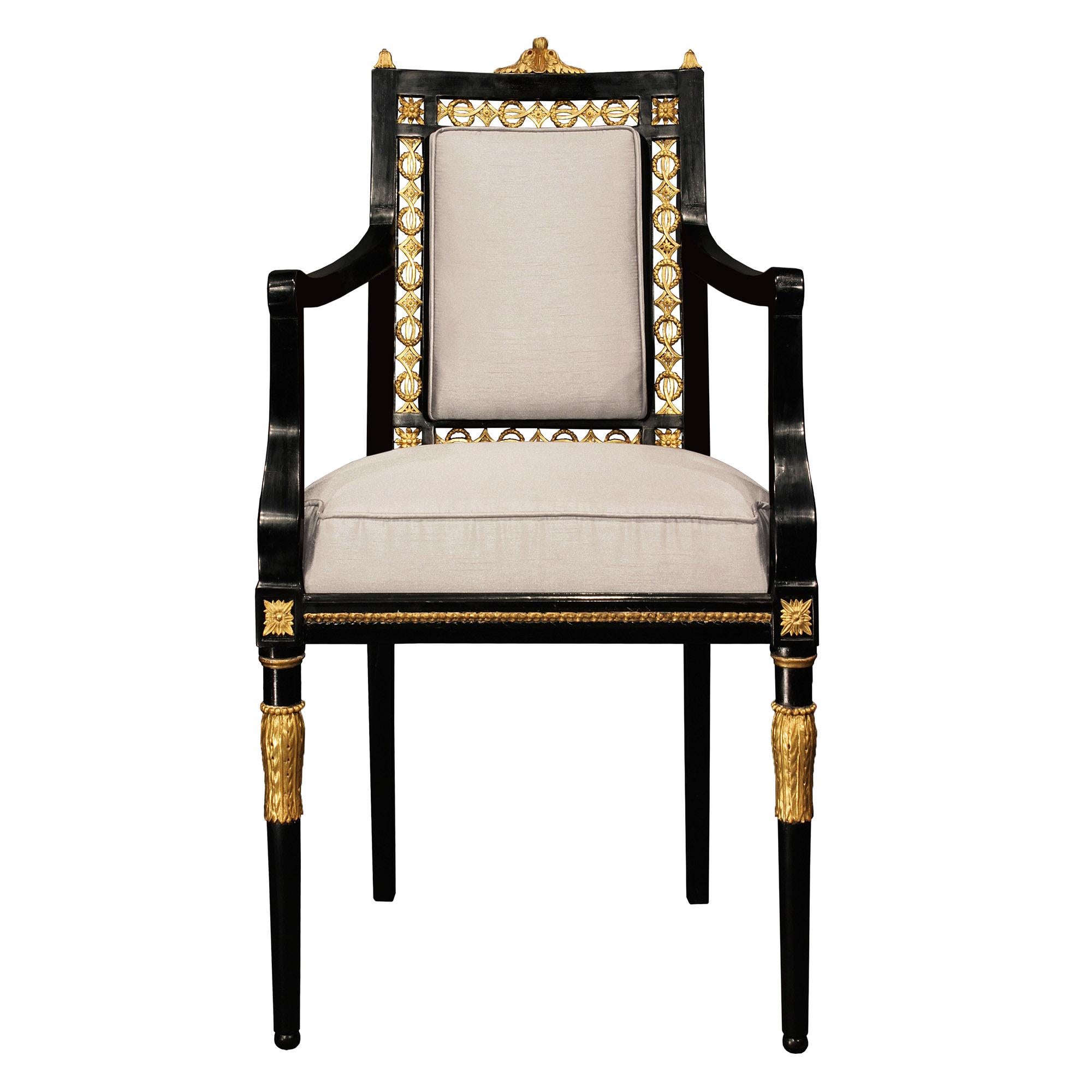 A very unique and extremely refined set of sixteen Italian early 19th century Louis XVI st. ebony and giltwood dining chairs. Each elegant chair is raised on tapered legs accented with giltwood carved acanthus leaves and top cap. At the straight