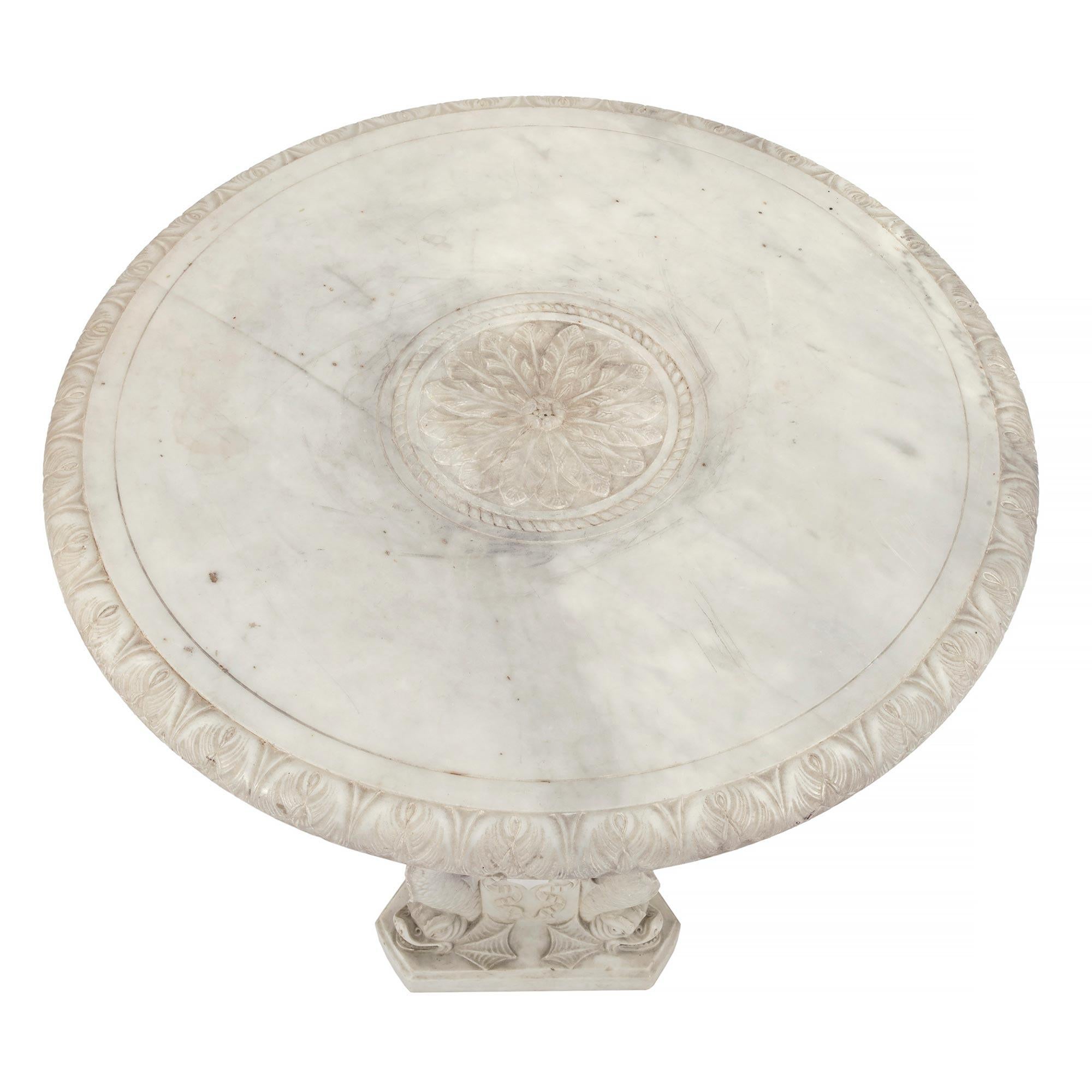 A fine Italian 19th century Louis XVI st. solid white carrara marble side table. The table is raised by a most decorative triangular base with cut corners and three most impressive and richly sculpted dolphins. The baluster shaped central support