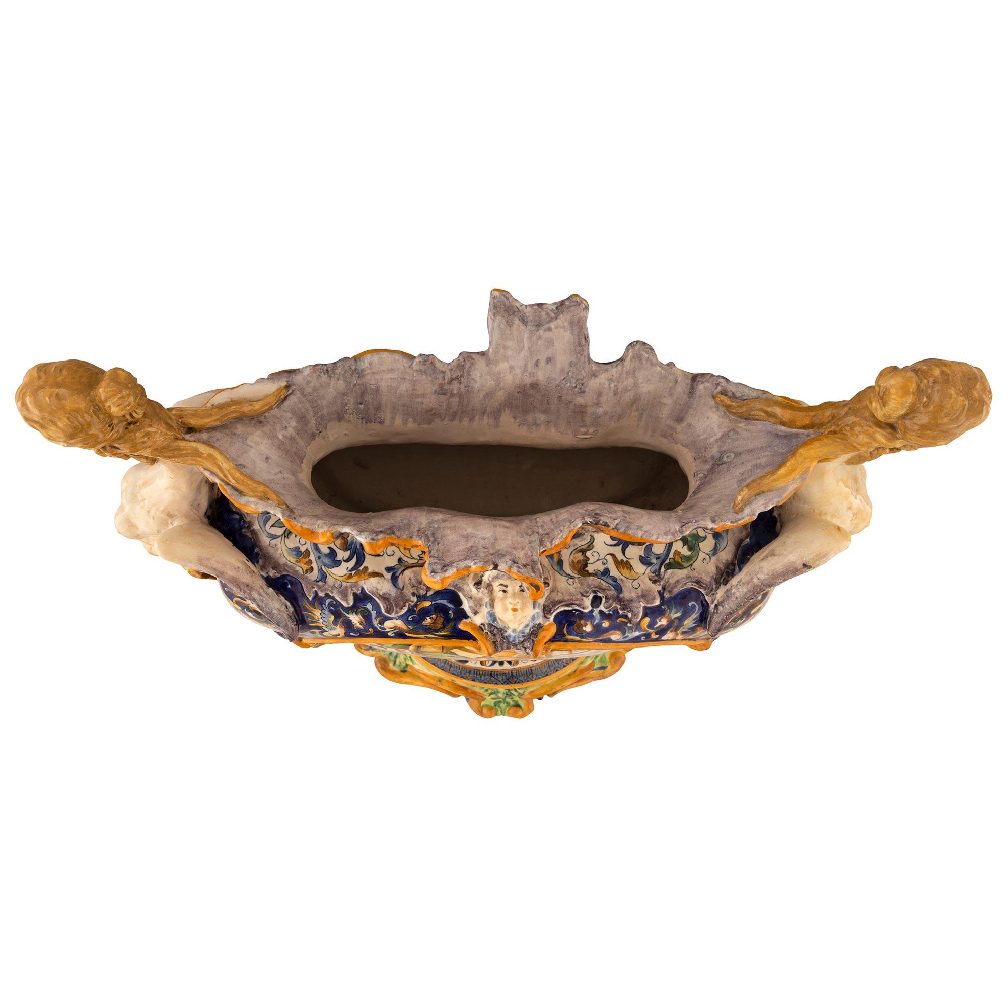 A beautiful and most decorative Italian 19th century Majolica porcelain centerpiece. The oblong shaped centerpiece is raised by lovely scalloped movements at the base with most decorative scrolled foliate designs and a lovely mottled wrap around