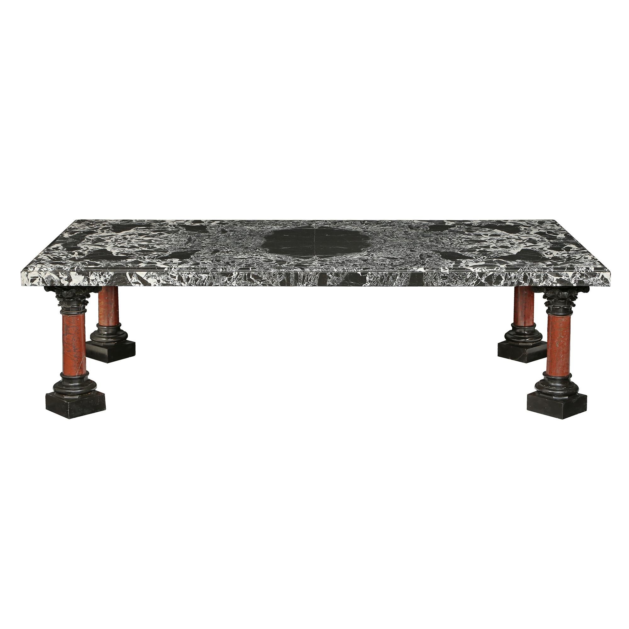 A sensational and large-scale Italian 19th-century marble coffee table. The coffee table is raised by four richly sculpted columns with black Belgian marble plinths and scrolled capitals and a Rouge Griote marble fut. The rectangular Grand Antique