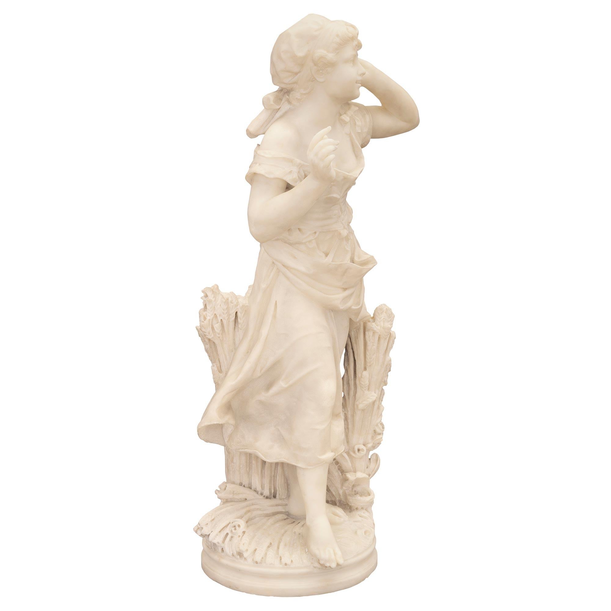 A stunning and masterfully executed Italian 19th century white Carrara marble statue of a young maiden in a wheat field. The statue is raised by an elegant circular base with a fine mottled border. Above is a beautiful young maiden dressed in a