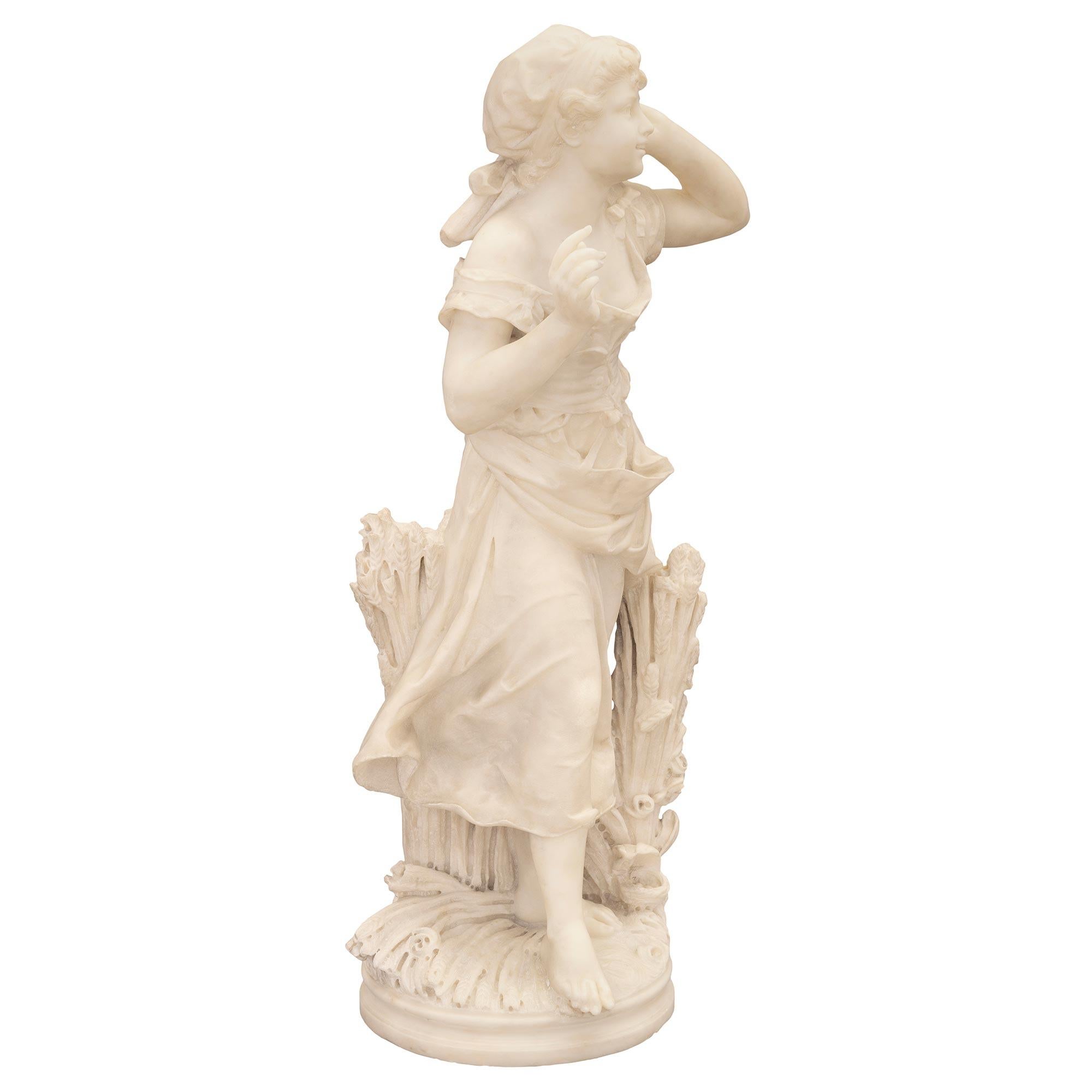 Statua in marmo bianco di Carrara del XIX secolo, splendida e magistralmente eseguita, raffigurante una giovane fanciulla in un campo di grano. La statua è sollevata da un'elegante base circolare con un raffinato bordo screziato. Qui sopra c'è una