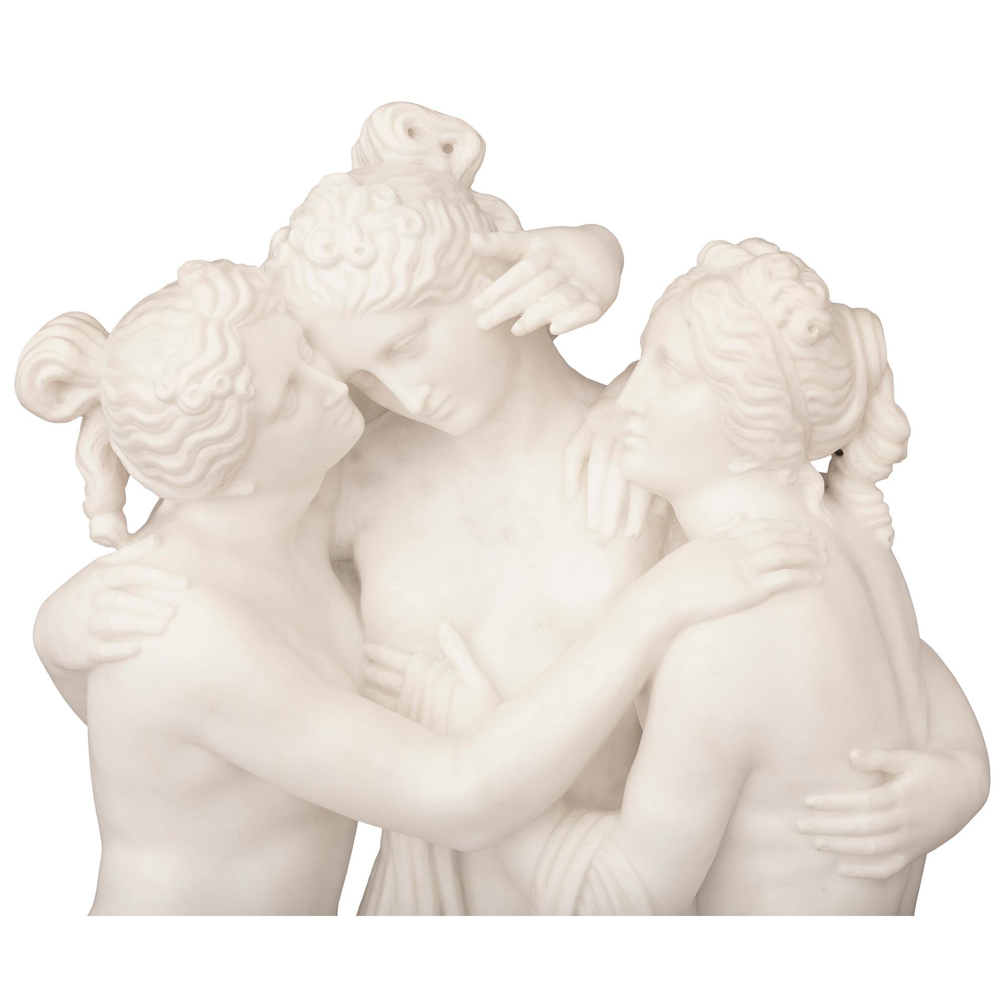 A stunning and extremely high quality Italian 19th century white carrara marble statue of the three graces after a model by Antonio Canova. The statue is raised by an oblong base with fine ground like designs with a pedestal draped in flowing