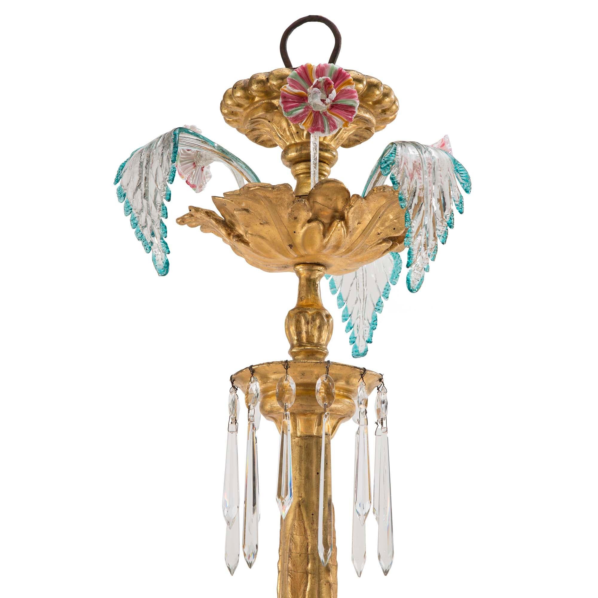 A stunning Italian 19th century Murano glass and giltwood ten light chandelier. At the bottom is a cut crystal inverted saucer, centered by a glass sphere pendant amidst kite shaped glass. The carved giltwood base has ten spiral cut glass arms with