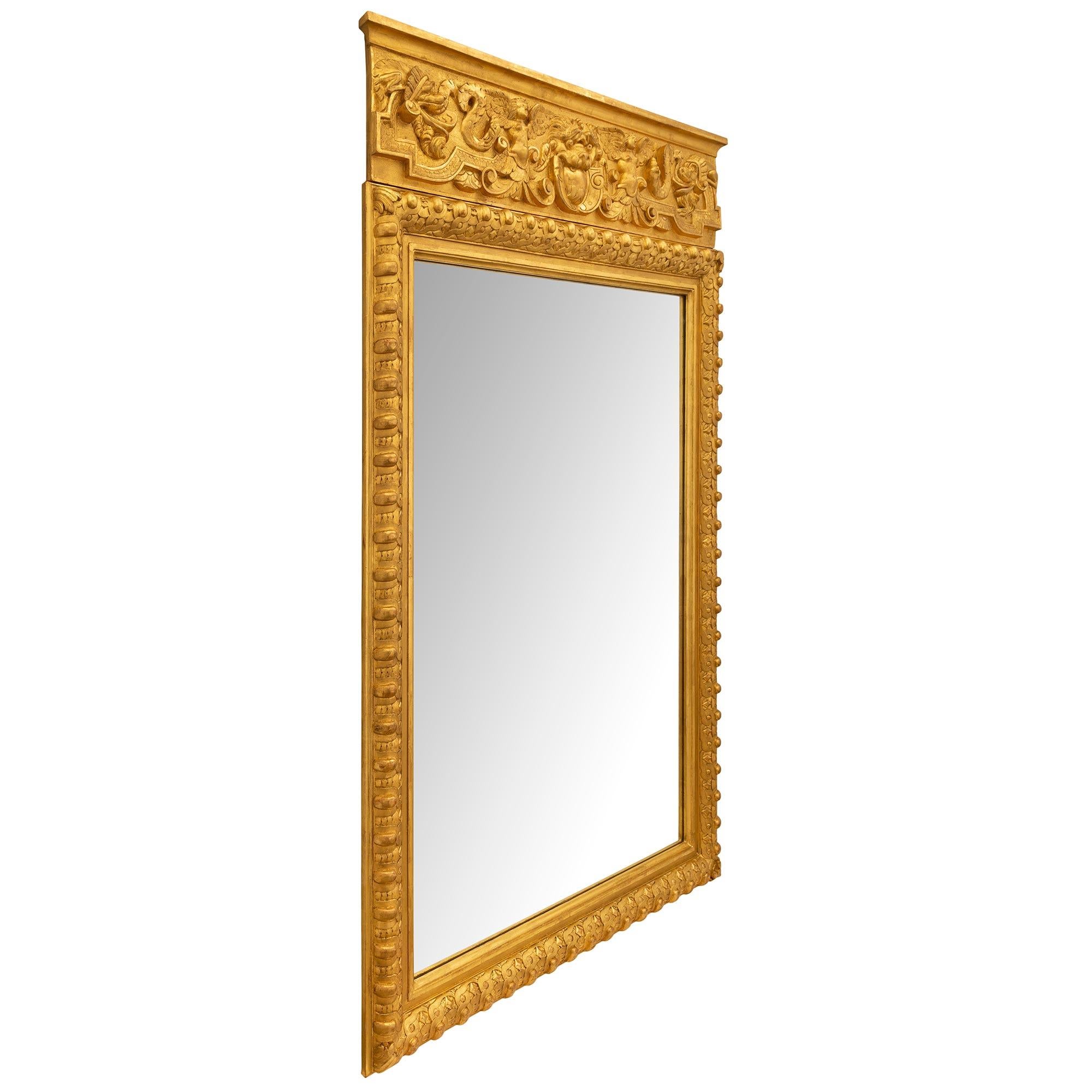 Remarquable miroir en bois doré de style néoclassique italien du XIXe siècle. Le miroir conserve sa plaque d'origine encadrée d'une fine bordure mouchetée et d'une exceptionnelle bordure enveloppante avec les motifs les plus décoratifs de Les Oves