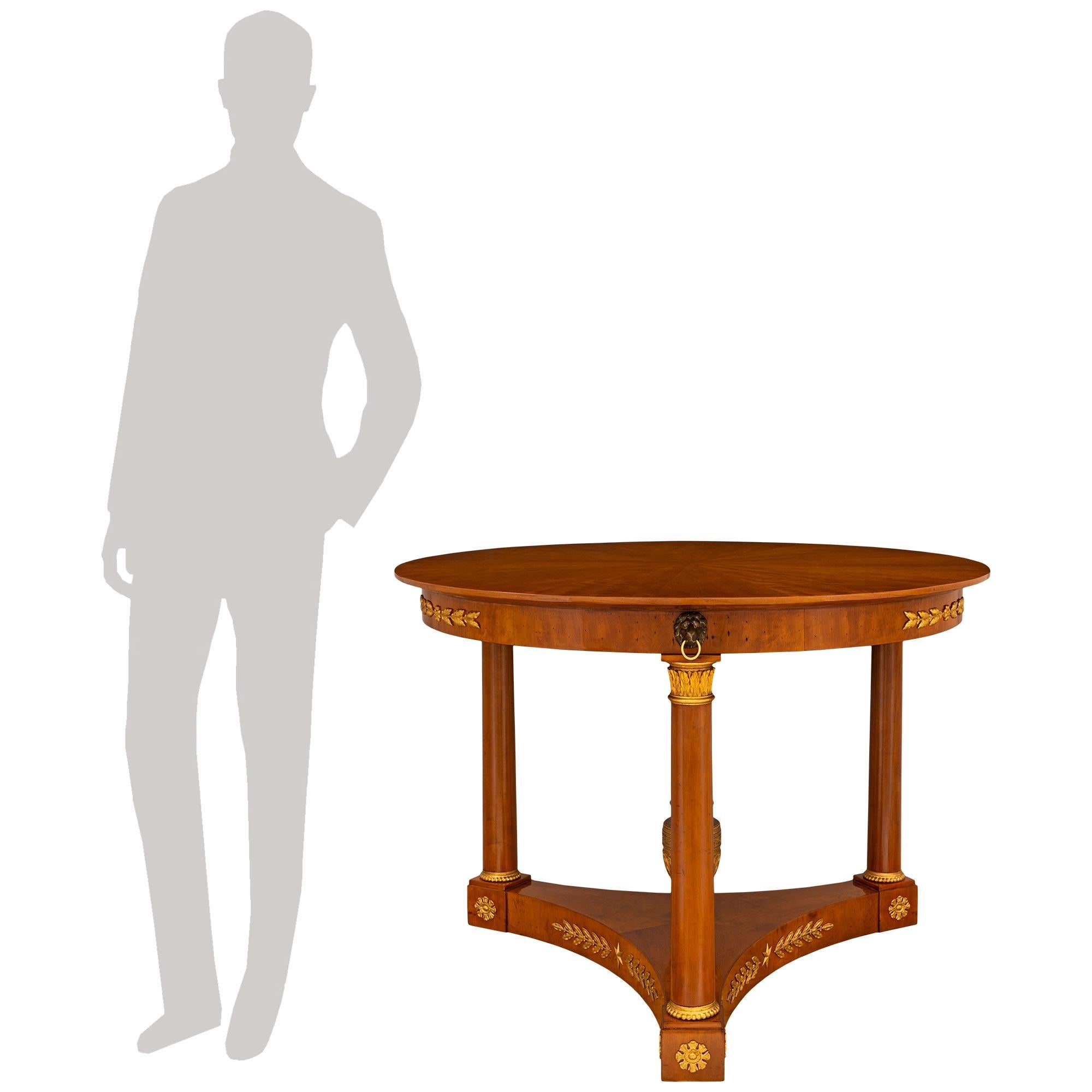 An elegant and most decorative Italian 19th century Neo-Classical st. Mahogany, Giltwood, patinated Wood, and Ormolu center table. This wonderful circular center table is raised on a triangular base with concave sides. Each side of the base