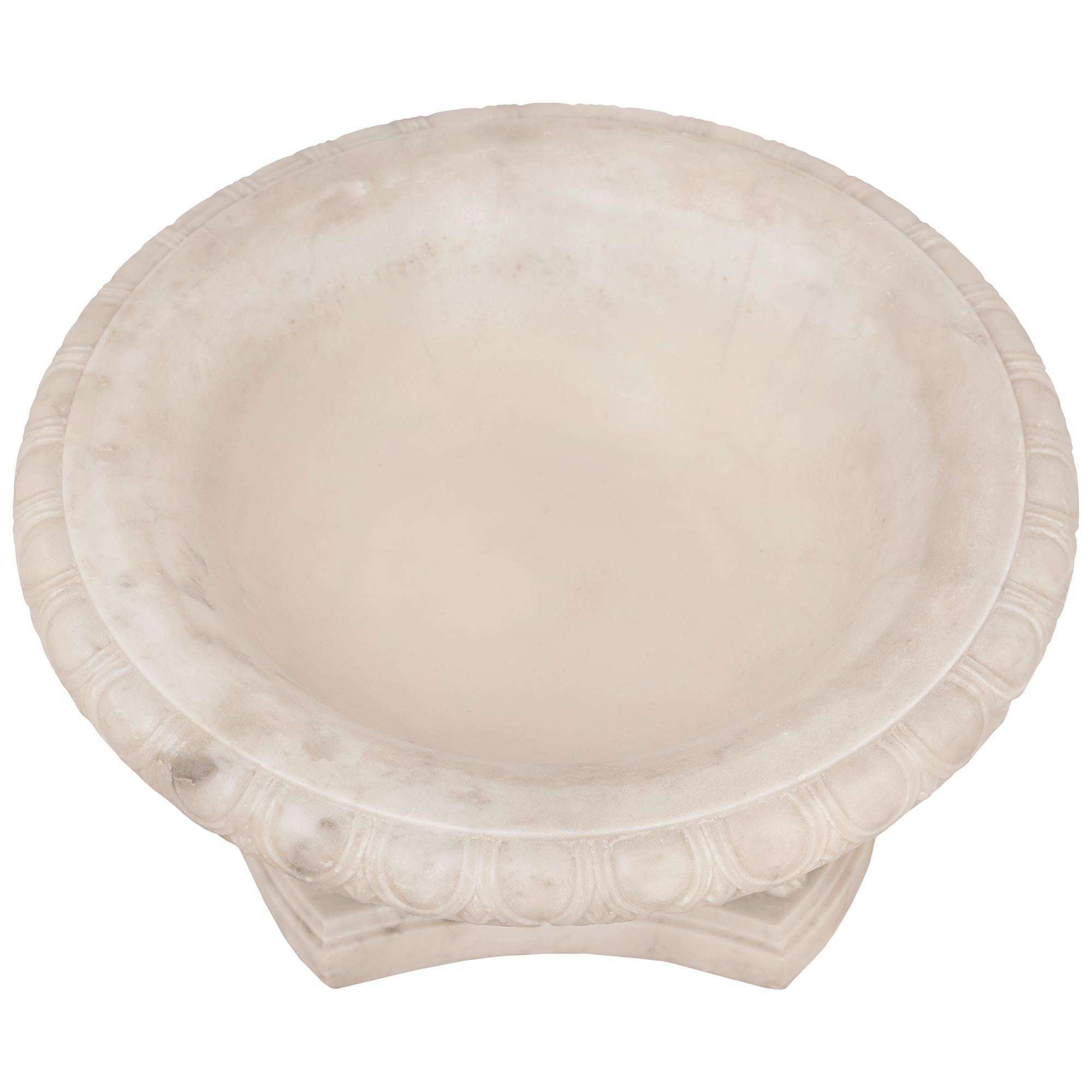 A striking and high quality Italian 19th century Neo-Classical st. white Carrara marble centerpiece bowl. The bowl is raised by a triangular base with concave sides, cut corners and a fine wrap around double mottled border. Three handsome richly