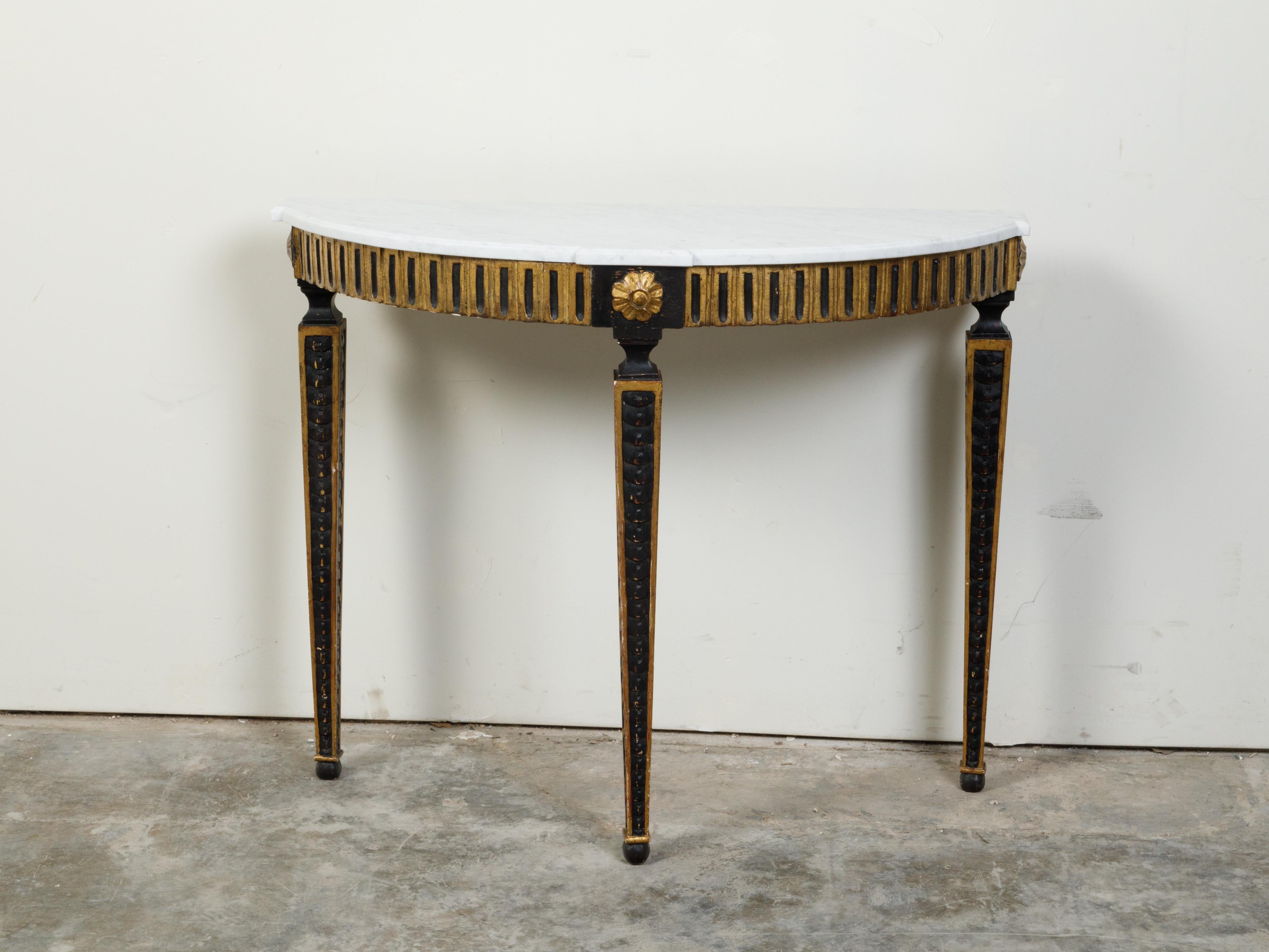 An Italian neoclassical style black parcel-gilt demi-lune console table from the 19th century, with white marble top and fluted motifs. Created in Italy during the 19th century, this demilune features a semi-circular white marble top with protruding
