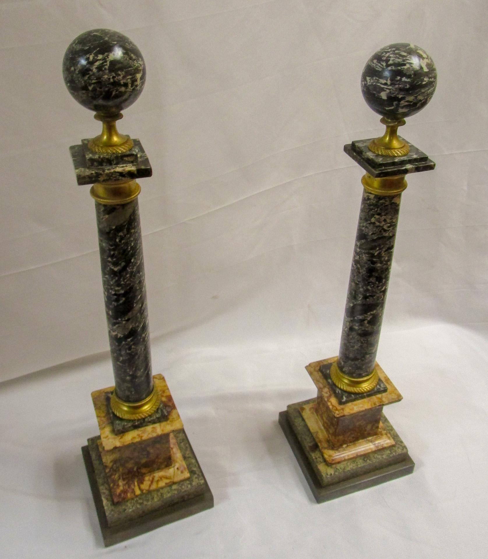 This outstanding and high quality pair of Italian 19th century Neo-Classical style Grand Tour period columns feature embossed gilded ormolu and  orb finials atop.
They are raised by square brass bases with a stepped design and fine ormolu bands.