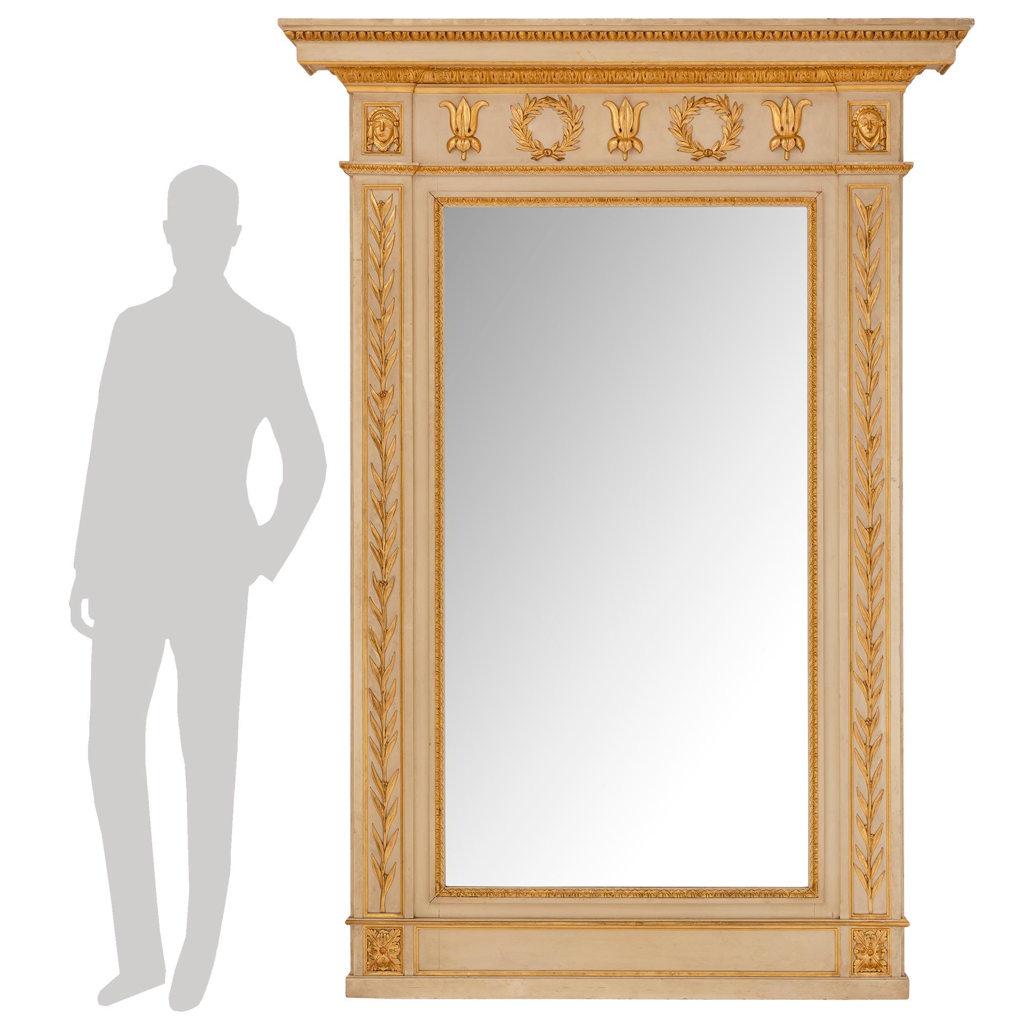 Magnifique miroir néoclassique italien du XIXe siècle en bois patiné et doré. La plaque de miroir d'origine est enchâssée dans une magnifique bordure en bois doré et feuillagé. De belles branches de laurier s'étendent de chaque côté du cadre patiné
