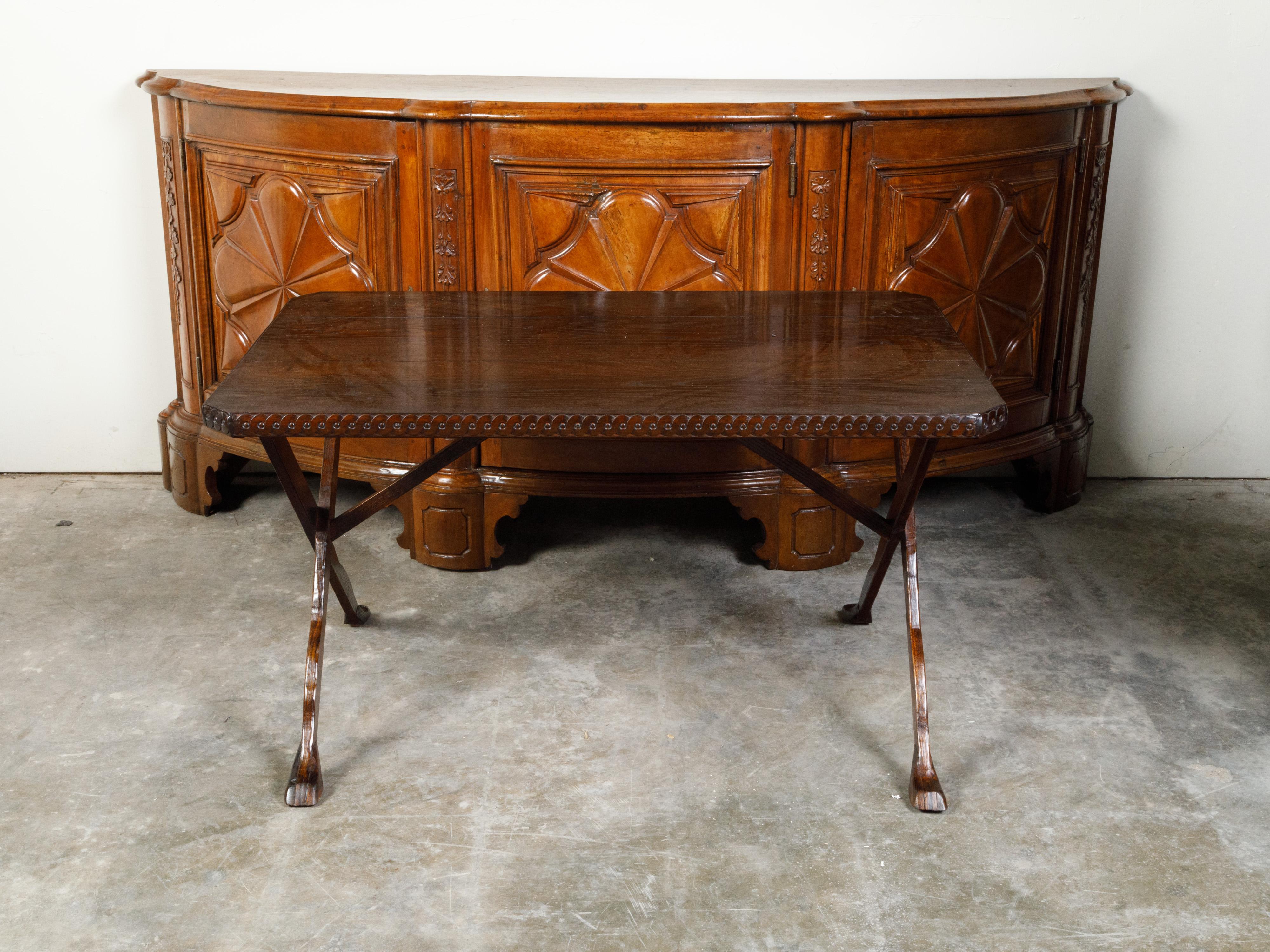An Italian oak side table from the 19th century, with carved guilloche friezes and X-form legs. Created in Italy during the 19th century, this oak side table features a rectangular planked top with canted corners, adorned with a Neoclassical style