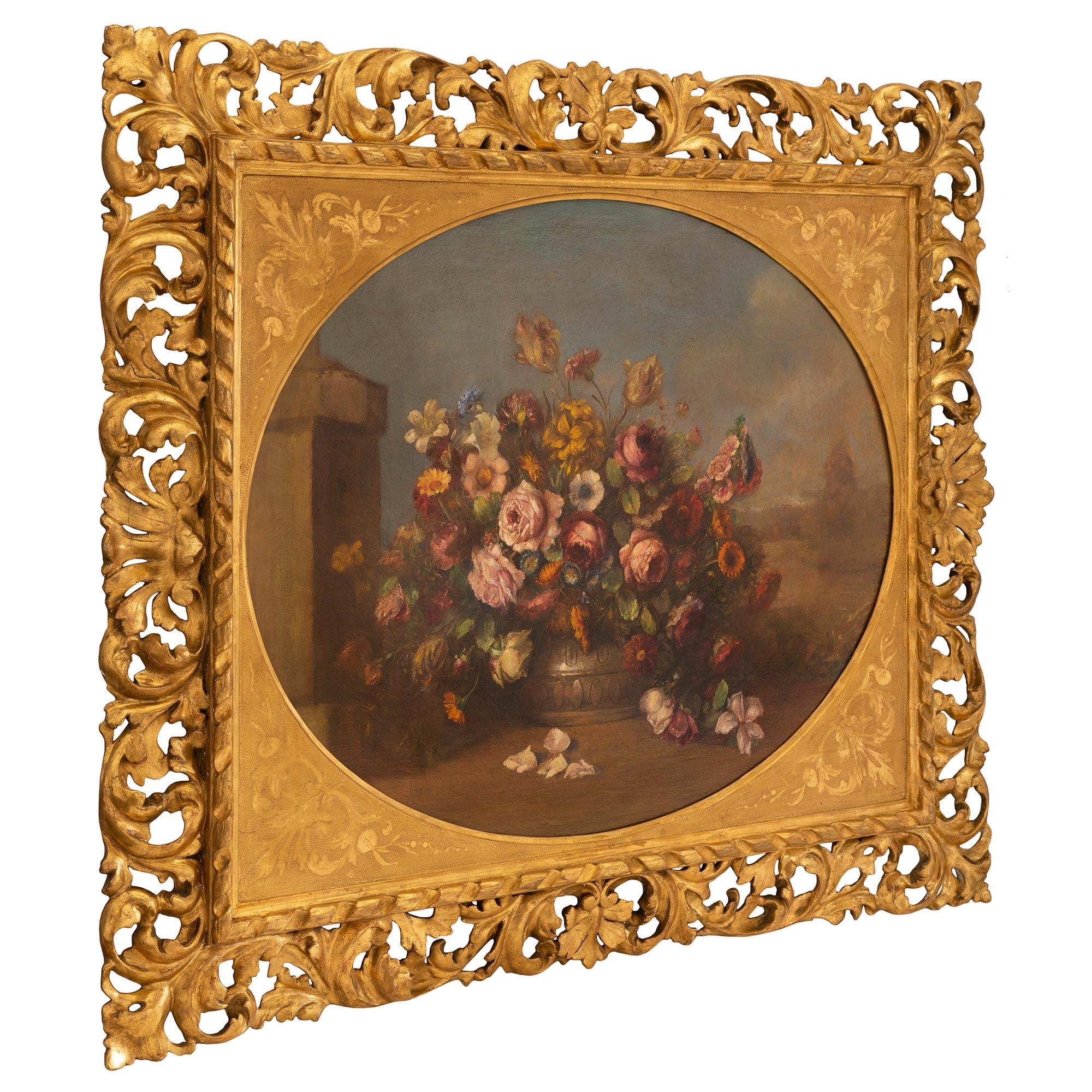An outstanding Italian 19th century oil on canvas still life painting. The highly detailed painting depicts a vibrant and charming bouquet of flowers in a vase, against blue sky. The painting is framed within a pierced giltwood frame with richly