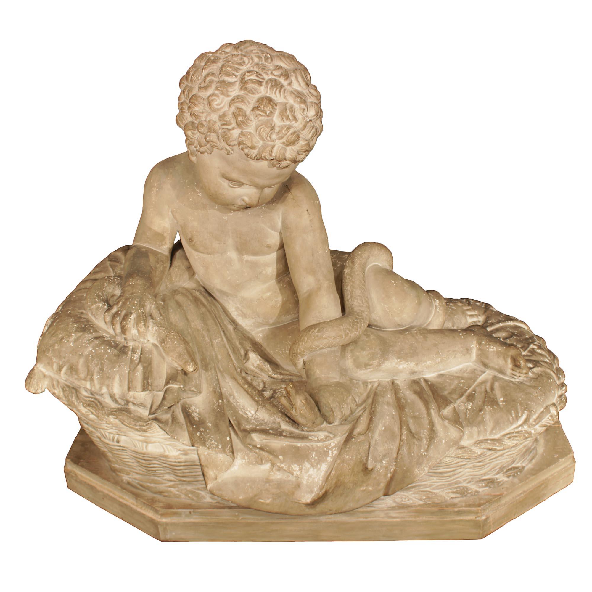 A very decorative Italian 19th century plaster statue of young baby Hercules. The statue is raised on an elongated hexagonal patinated base. Above is a wicker designed bed with large pillow and bedding. A small cherub resting in bed is focused on