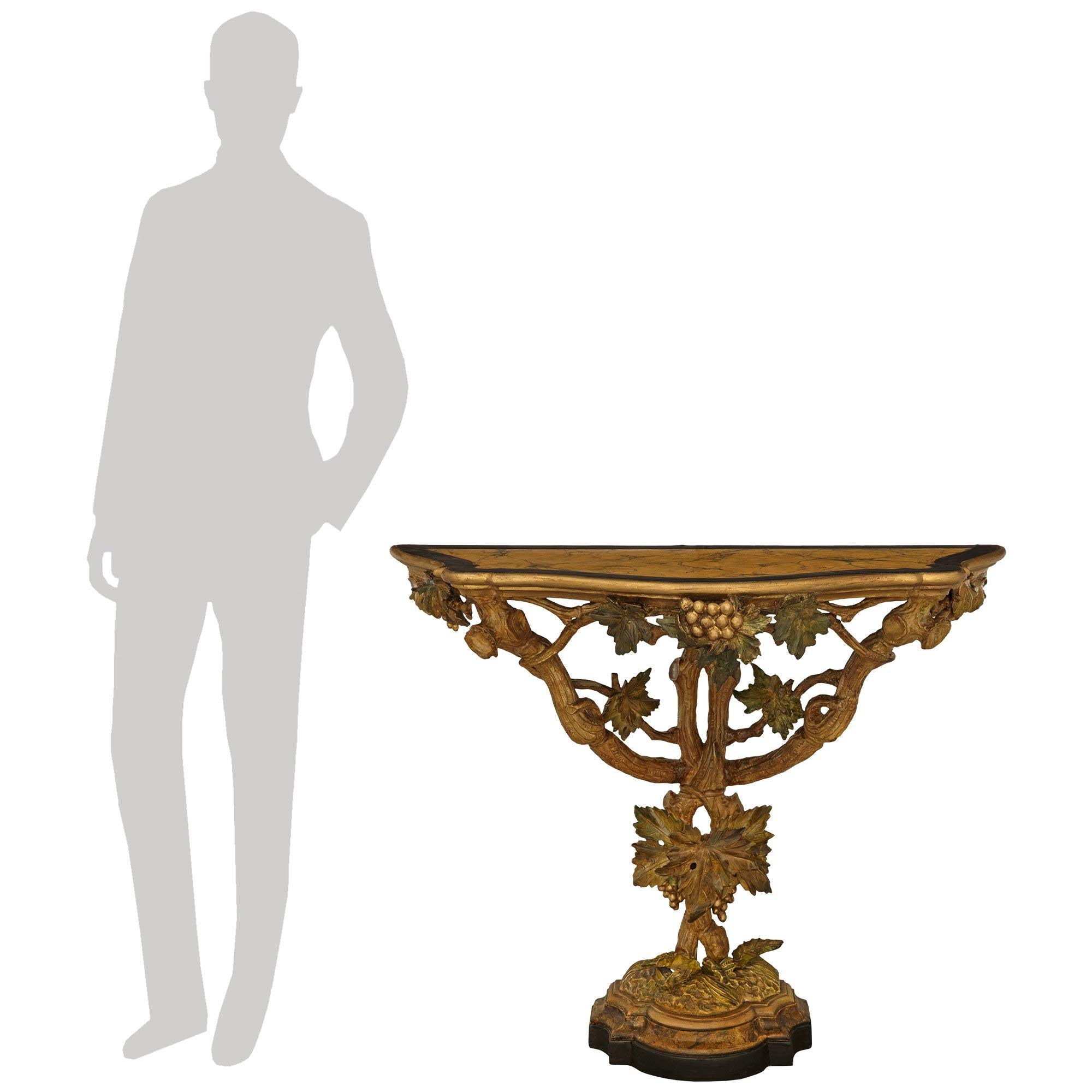 A wonderfully decorative Italian 19th century Polychrome, patinated Wood and Gilt console. This most unique console is raised by a mottled patinated Wood base with a faux marble coved band before the simulated ground with leaves and two vertical