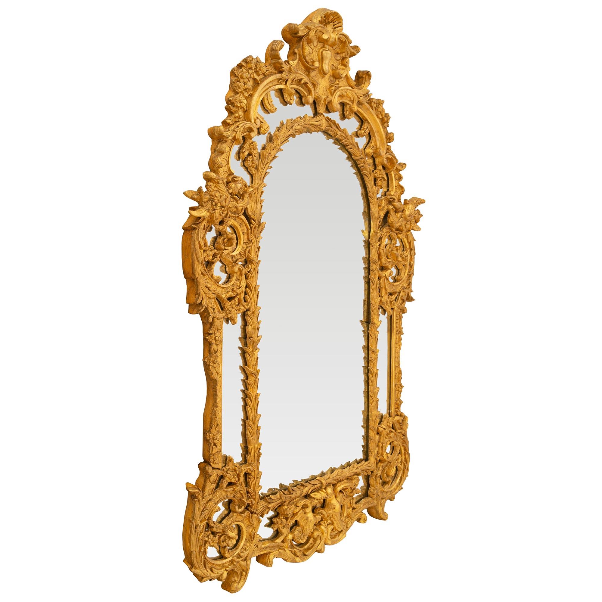 A beautiful Italian 19th century Regence st. double framed giltwood mirror. The mirror retains all of its original mirror plates throughout with the central mirror plate set within a richly carved wrap around foliate band. At the base are two birds