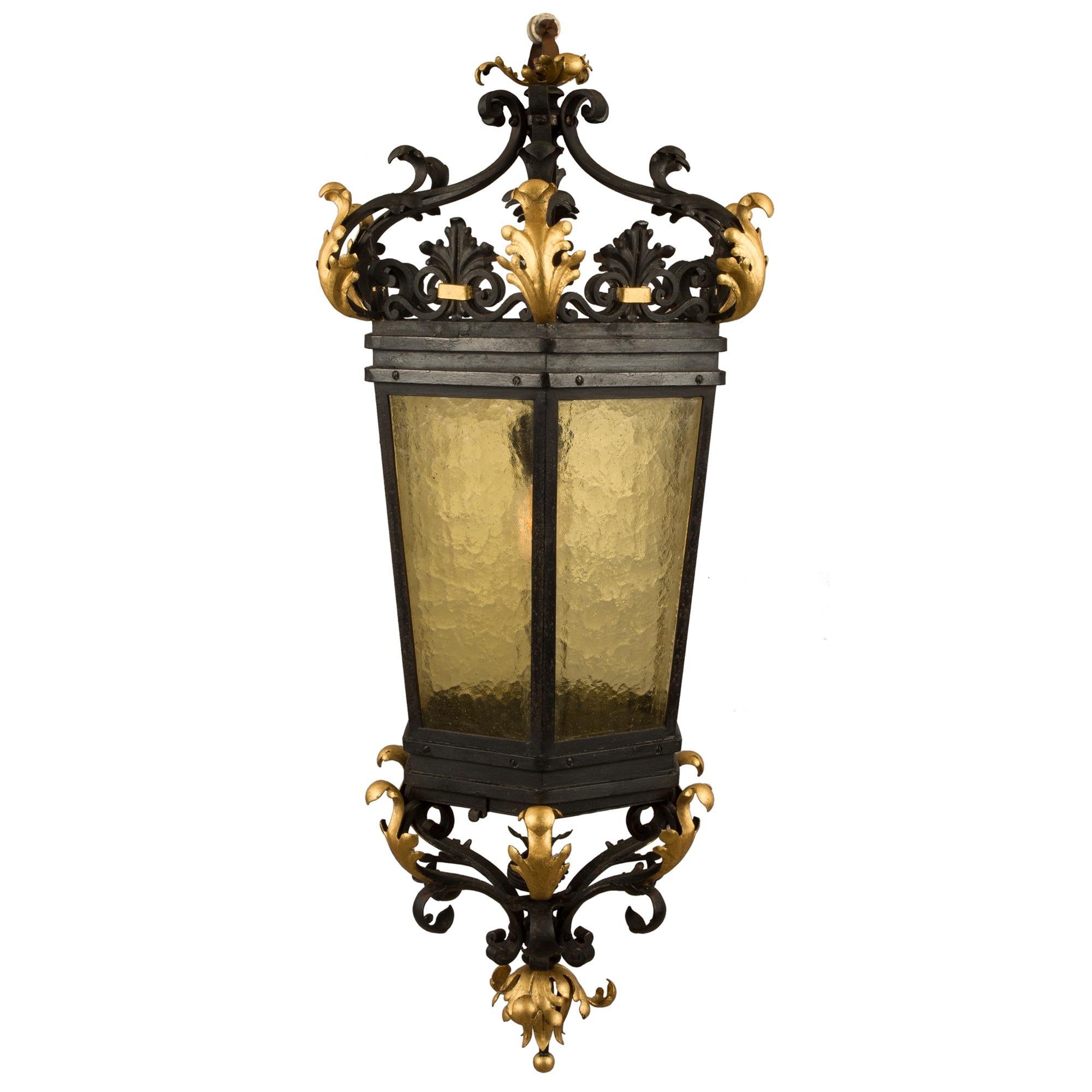 A beautiful Italian 19th century Renaissance st. iron, gilt iron and glass hexagonal lantern. The lantern is centered by most decorative and charming scrolled movements with lovely gilt metal accent leaves. The tapered hexagonal body retains its