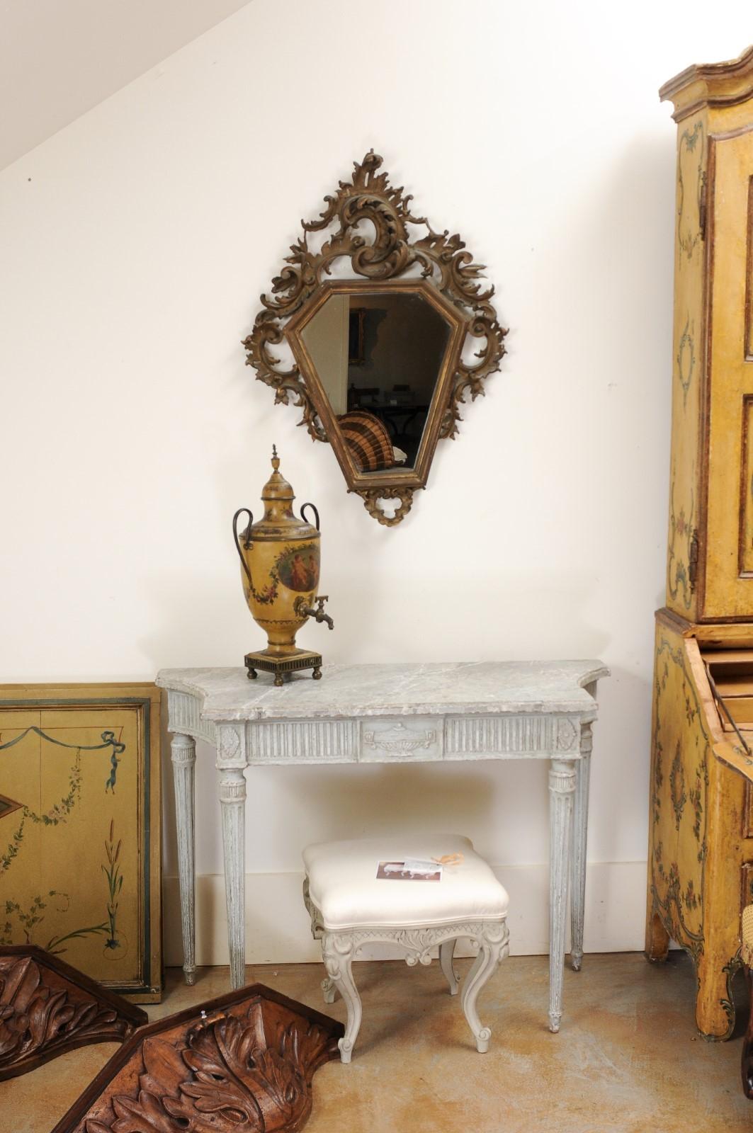 An Italian Rococo style carved mirror from the 19th century, with traces of gilt. Created in Italy during the 19th century, this piece features a polygonal mirror plate surrounded by an eye-catching carved frame showcasing Rocailles c-scrolls and
