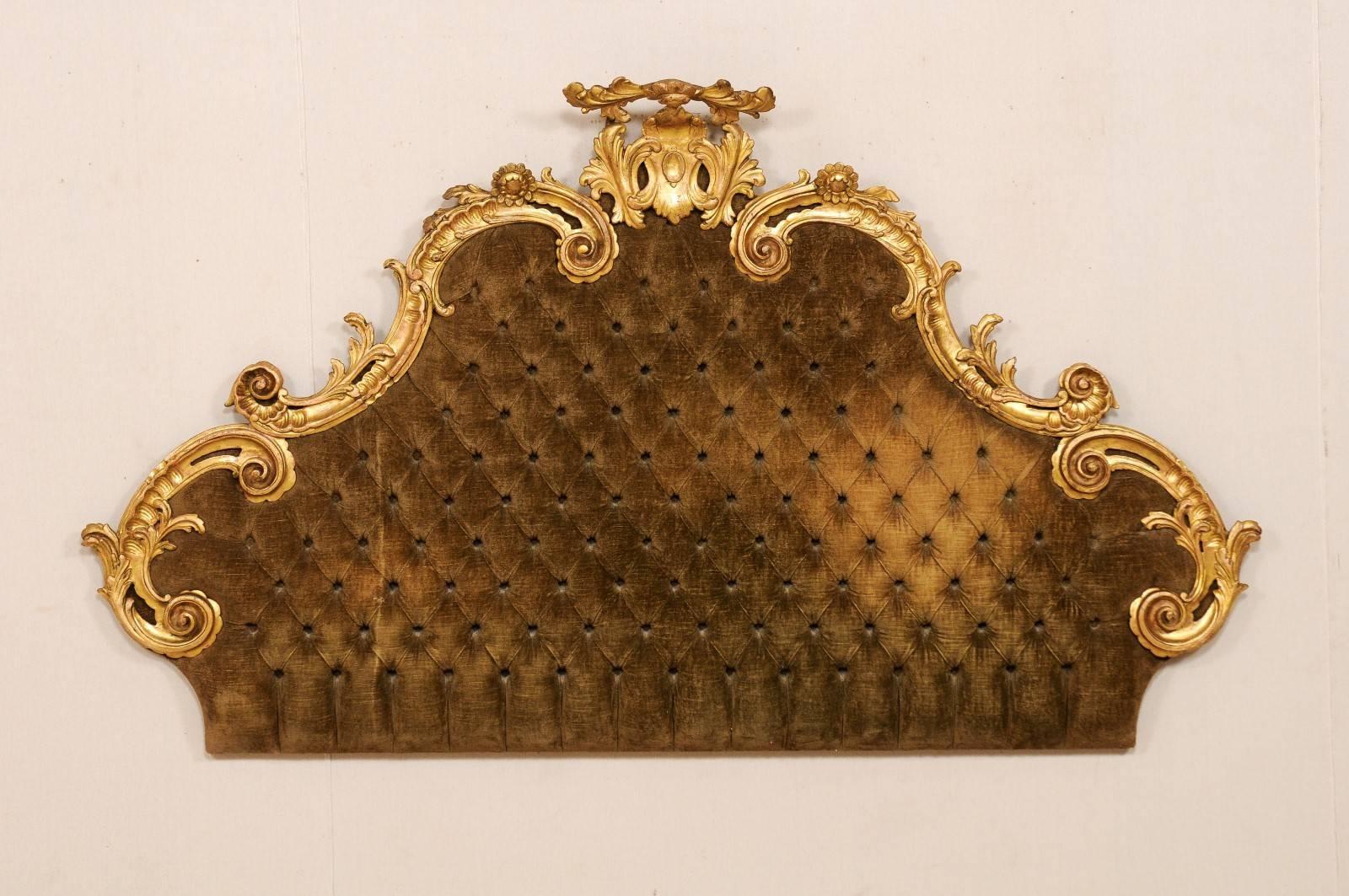 An Italian 19th century Rococo style lavishly carved and tufted headboard for bed. This opulent Italian antique headboard features a balanced giltwood carved crest of scrolling acanthus leaves with floral accents, nice pierced details and lovely
