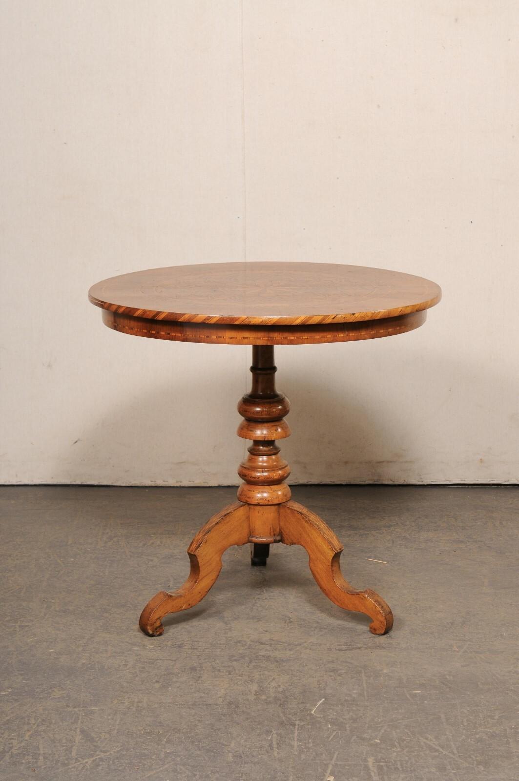 An Italian round occasional table with decorative inlay top from the 19th century. This antique table from Italy features a 31